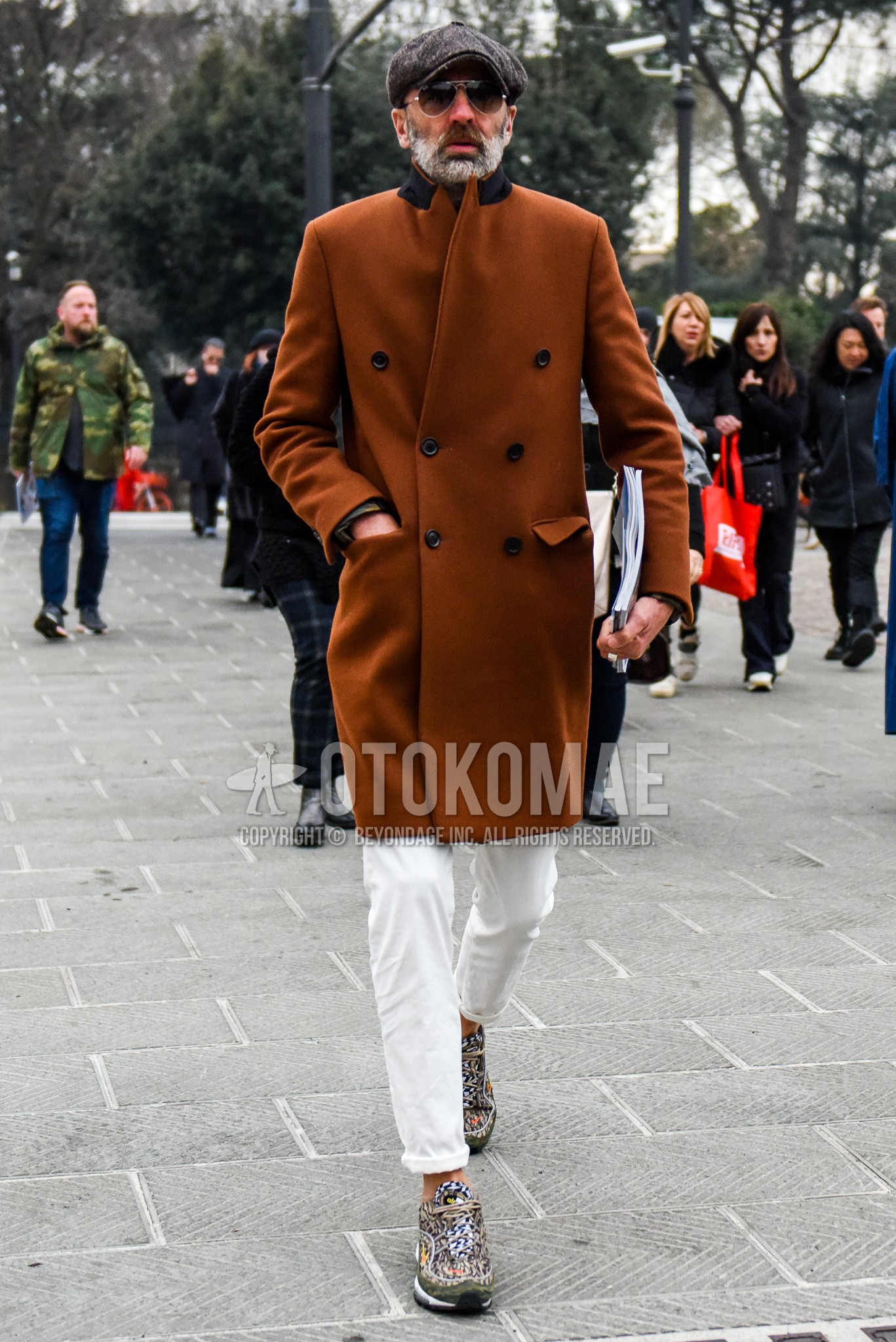 Men's autumn winter outfit with gray plain hat, gold plain sunglasses, brown plain chester coat, white plain denim/jeans, multi-color low-cut sneakers.