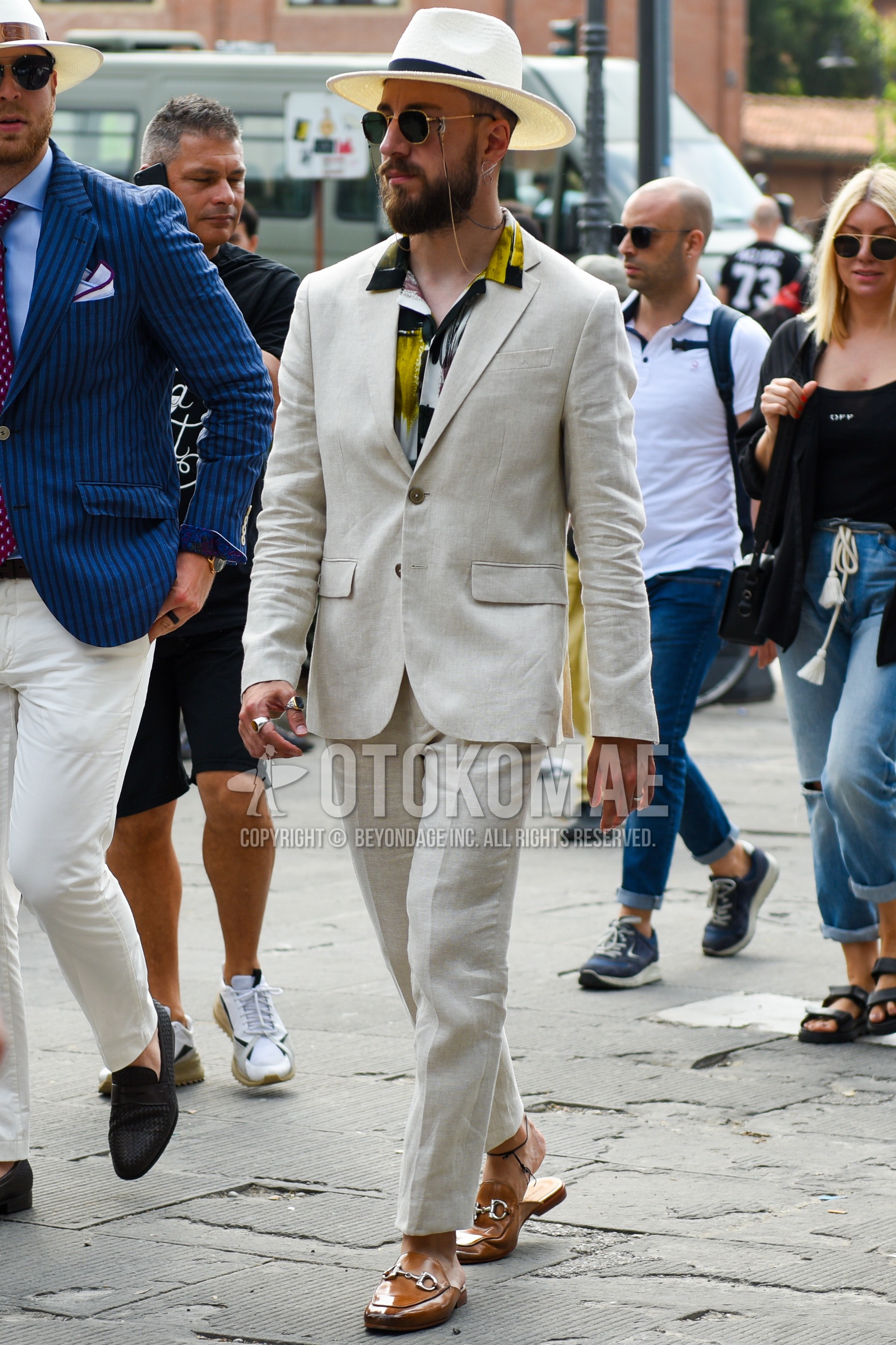Men's spring summer autumn outfit with beige plain hat, black gold plain sunglasses, multi-color plain shirt, beige leather sandals, beige plain suit.