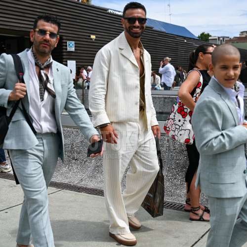 無地のサングラス、ベージュ無地のシャツ、開襟　オープンカラーの白ストライプのシャツ、白ストライプのスラックス、白ローファーの革靴、白スエードシューズの革靴、ブラウンレタードのトートバッグ、白ストライプのカジュアルセットアップを合わせた夏春のメンズコーデ・着こなし。