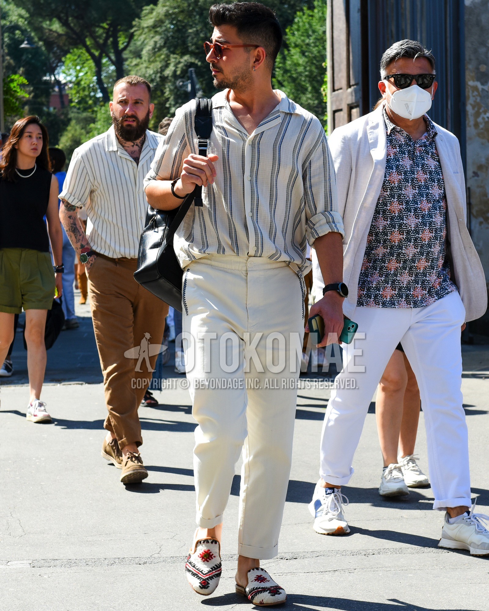 Men's spring summer outfit with brown plain sunglasses, beige stripes shirt, white plain cotton pants, white plain ankle pants, white  espadrille, black plain backpack.