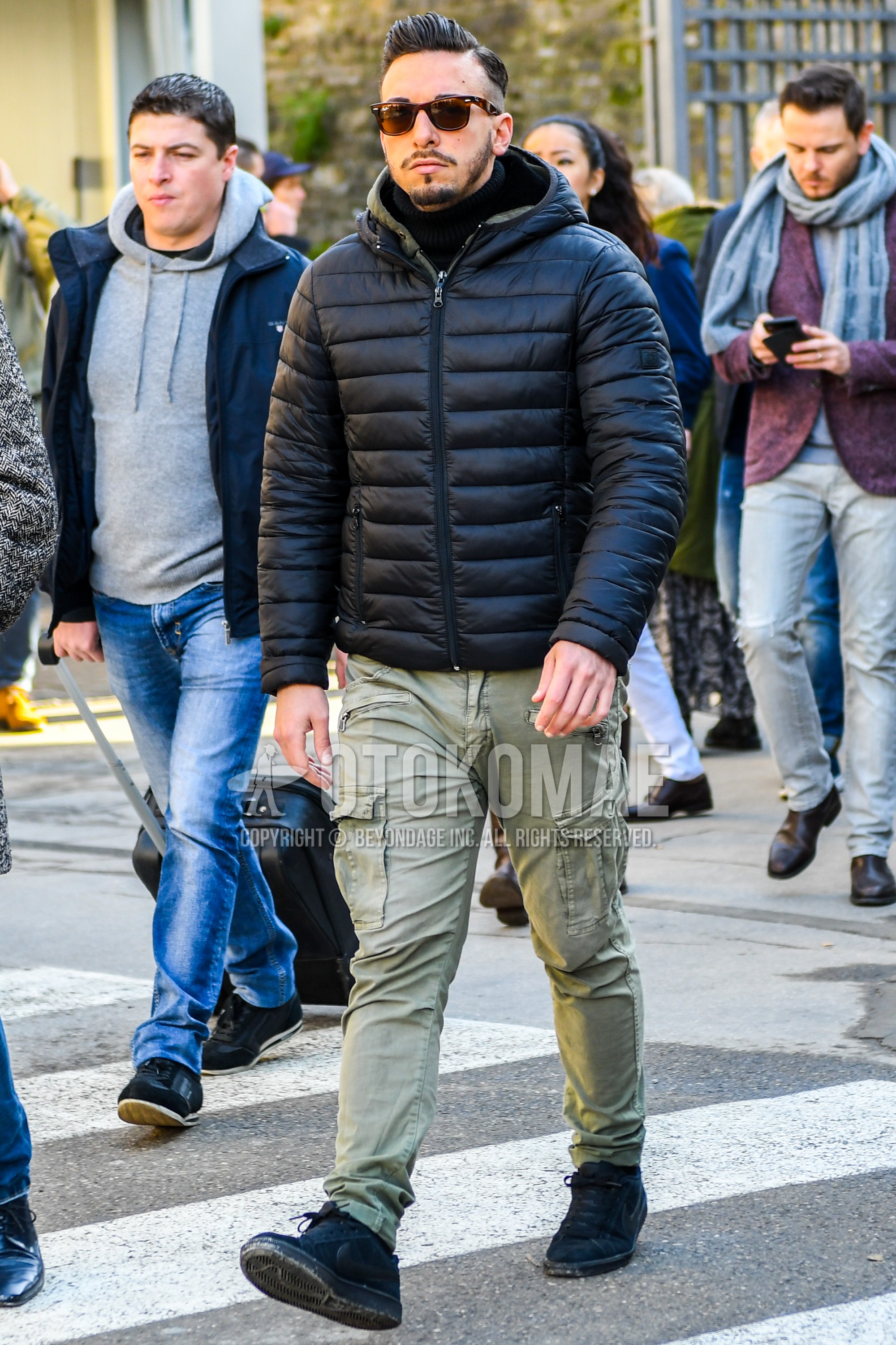 Men's winter outfit with plain sunglasses, black plain down jacket, black plain turtleneck knit, olive green plain cargo pants, black low-cut sneakers.