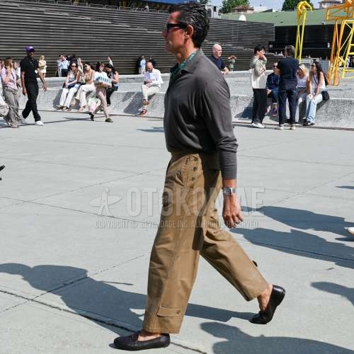 黒無地のサングラス、黒・グリーンストールのバンダナ/ネッカチーフ、グレー無地のポロシャツ、ベージュ無地のチノパン、ブラウンローファーの革靴を合わせた春夏のメンズコーデ・着こなし。