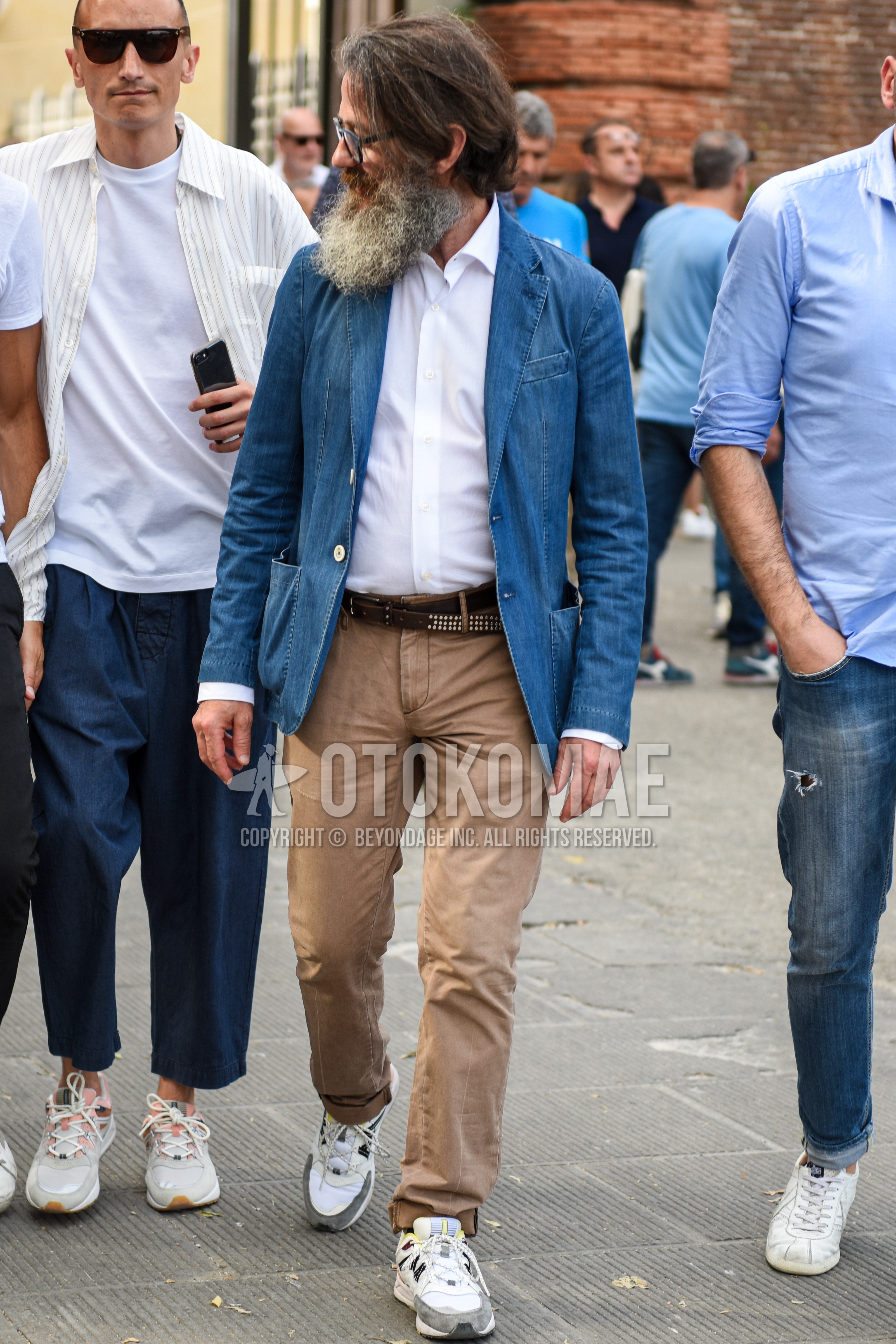 Men's spring summer autumn outfit with blue plain tailored jacket, white plain shirt, brown plain leather belt, brown plain cotton pants, white low-cut sneakers.