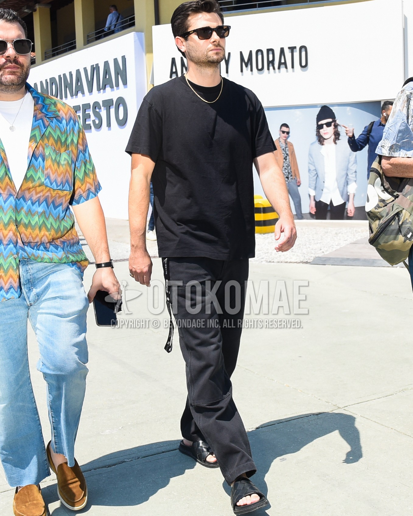 Men's spring summer outfit with black plain sunglasses, black plain t-shirt, black plain baker pants, black leather sandals.