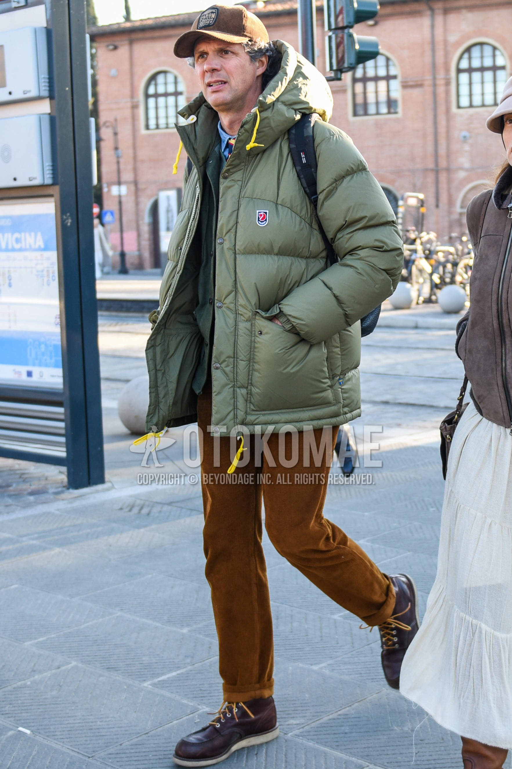 Men's winter outfit with brown graphic baseball cap, olive green plain down jacket, blue plain denim shirt/chambray shirt, brown plain winter pants (corduroy,velour), brown work boots, multi-color leopard necktie.