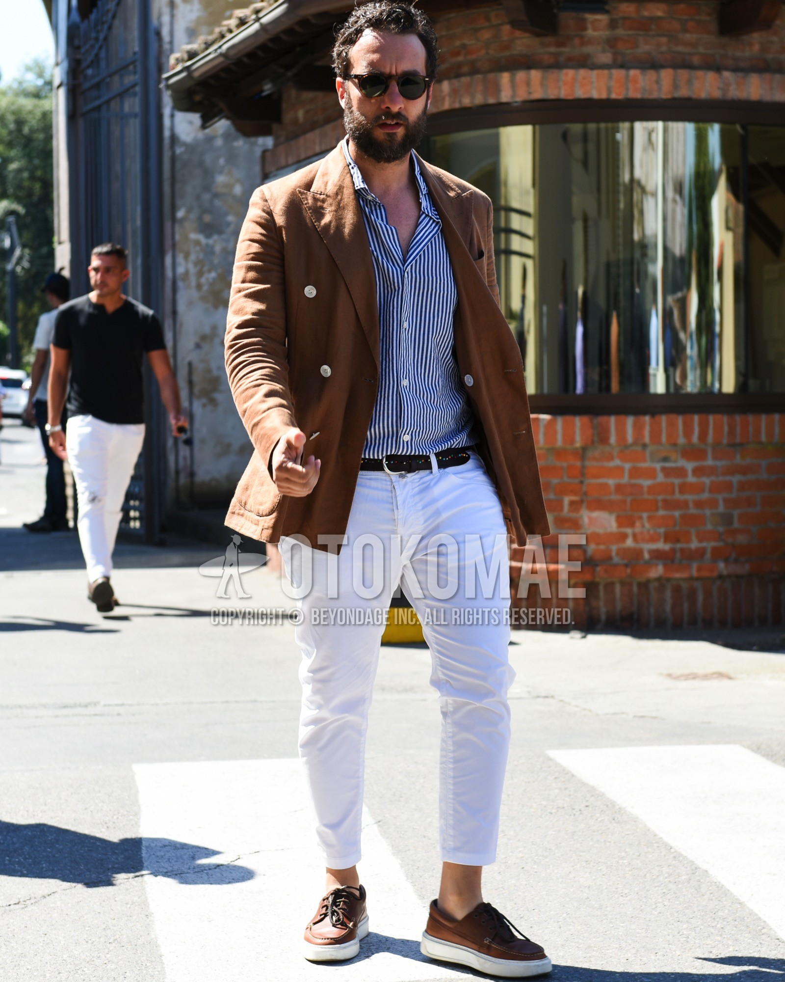 Men's spring summer outfit with brown tortoiseshell sunglasses, brown plain tailored jacket, navy white stripes shirt, black plain leather belt, white plain cotton pants, brown low-cut sneakers.