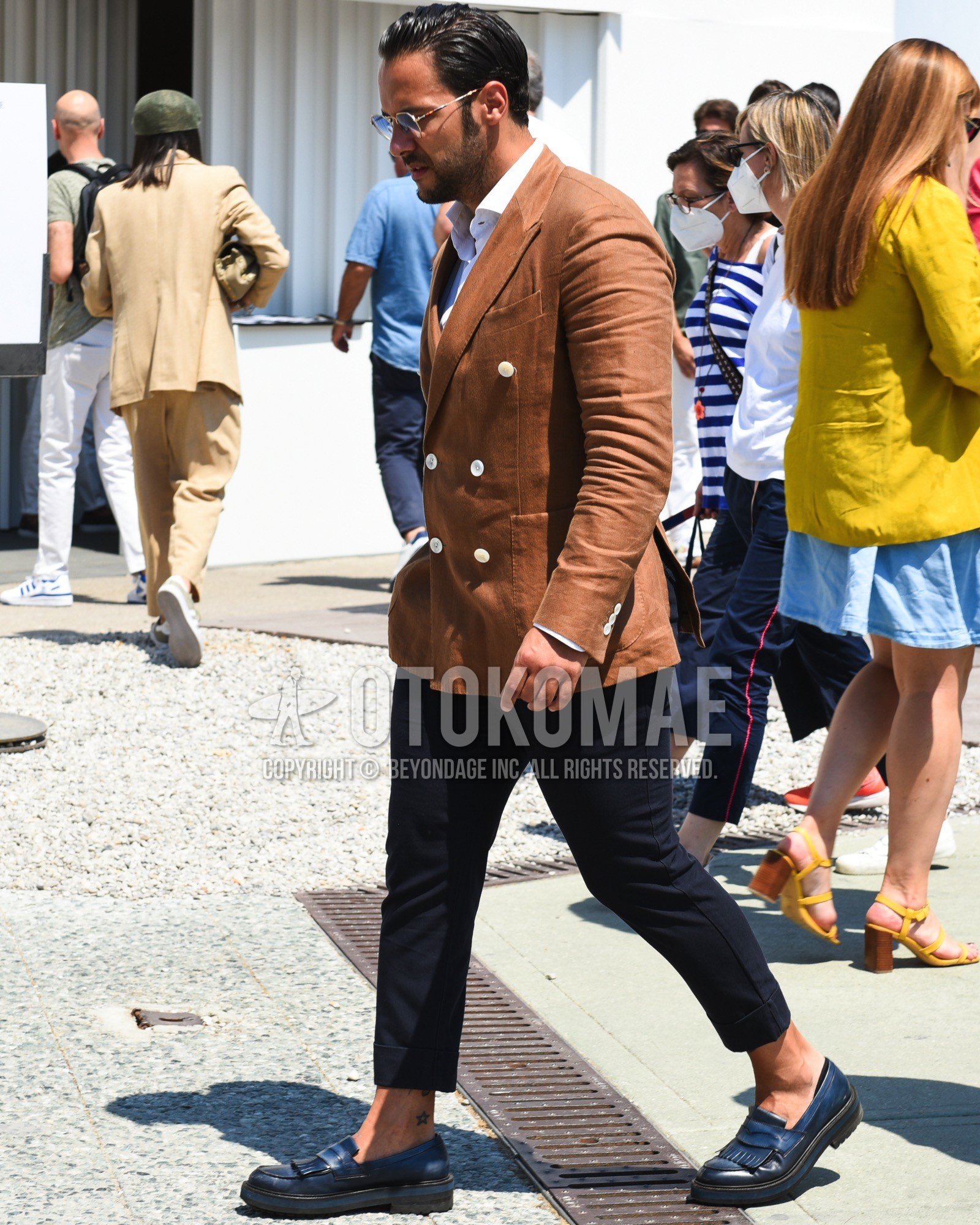 Men's spring summer outfit with gold plain sunglasses, brown plain tailored jacket, white plain shirt, black plain chinos, black coin loafers leather shoes.