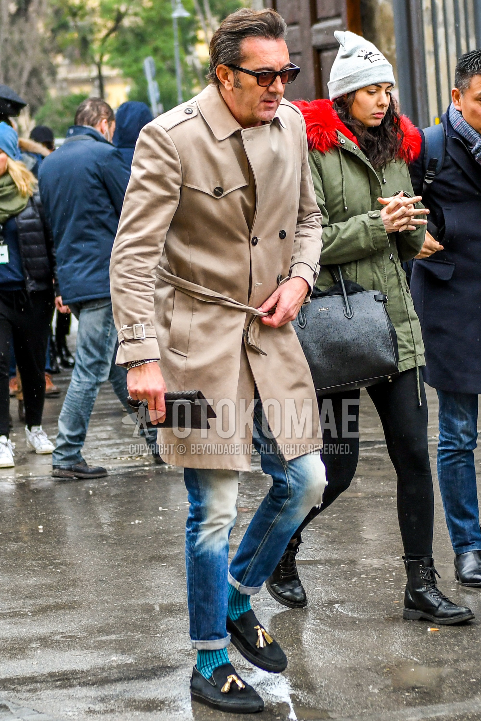 Men's autumn winter outfit with plain sunglasses, beige plain trench coat, blue plain denim/jeans, blue stripes socks, black  leather shoes.