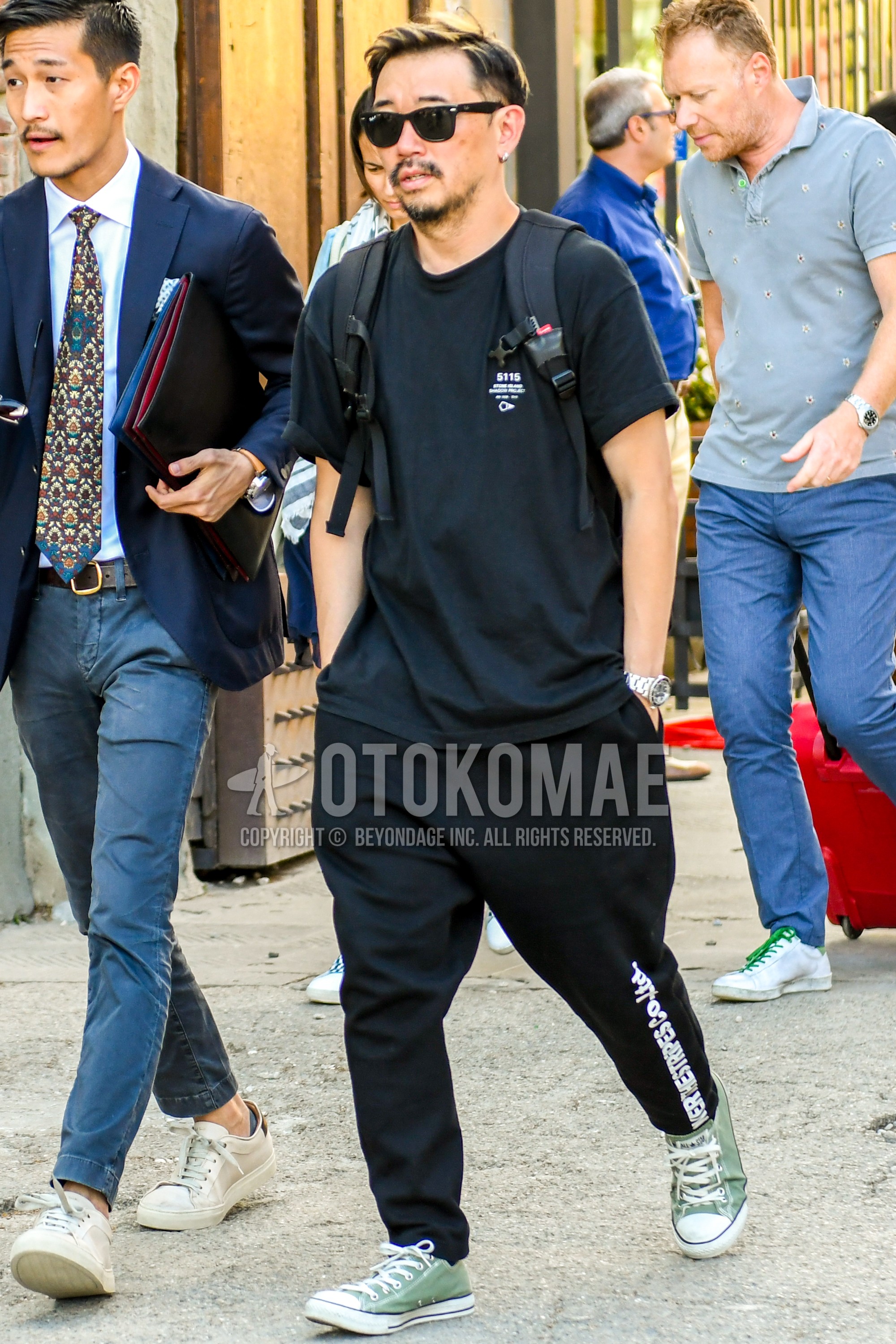 Men's summer outfit with plain sunglasses, black one point t-shirt, black graphic sweatpants, green low-cut sneakers.
