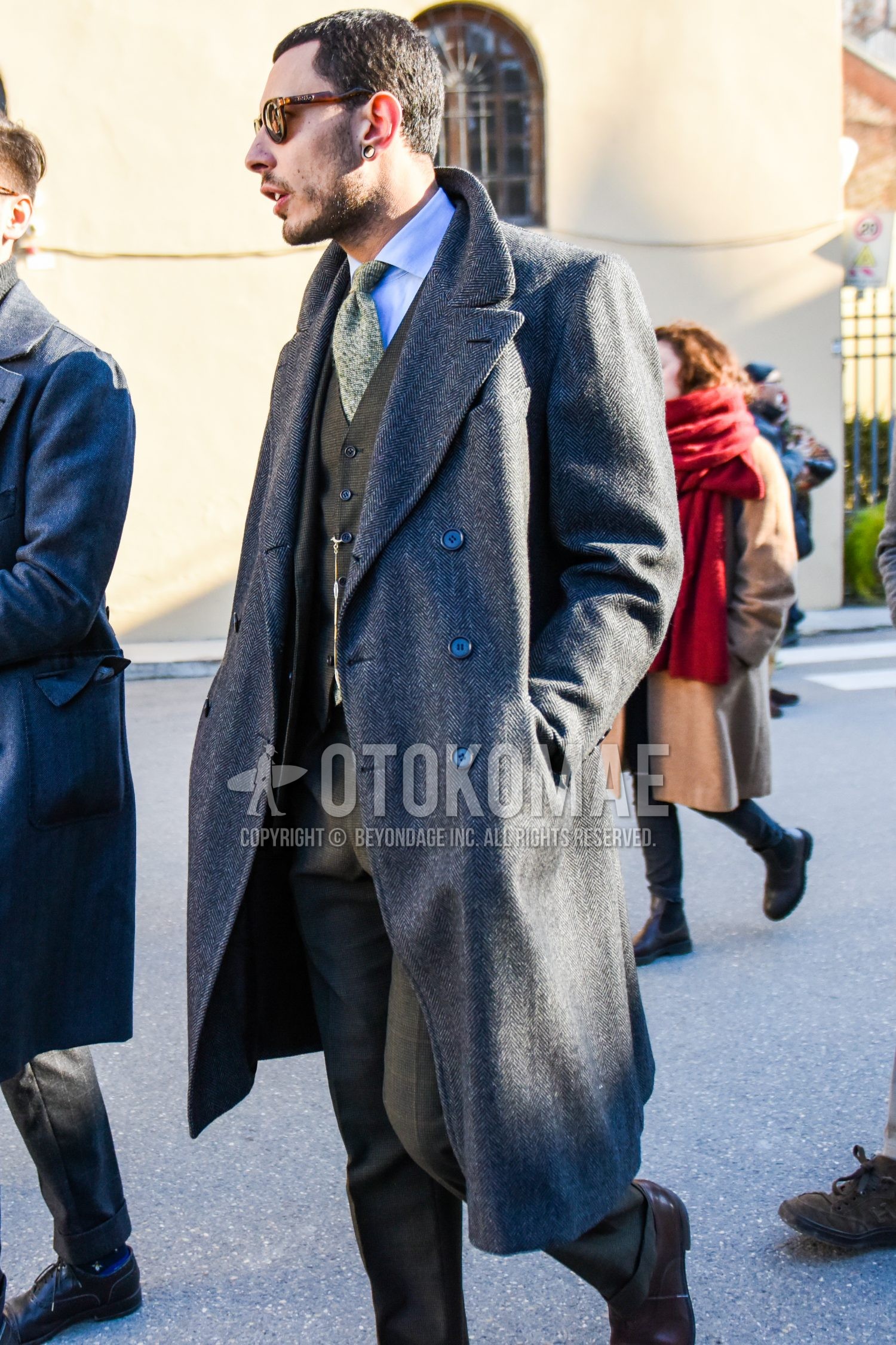 Men's autumn winter outfit with brown tortoiseshell sunglasses, gray plain chester coat, blue plain shirt, gray check three-piece suit, beige necktie necktie.