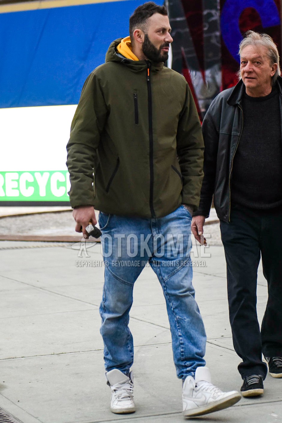 Men's spring autumn outfit with olive green plain hoodie, olive green plain hoodie, blue plain denim/jeans, white high-cut sneakers.