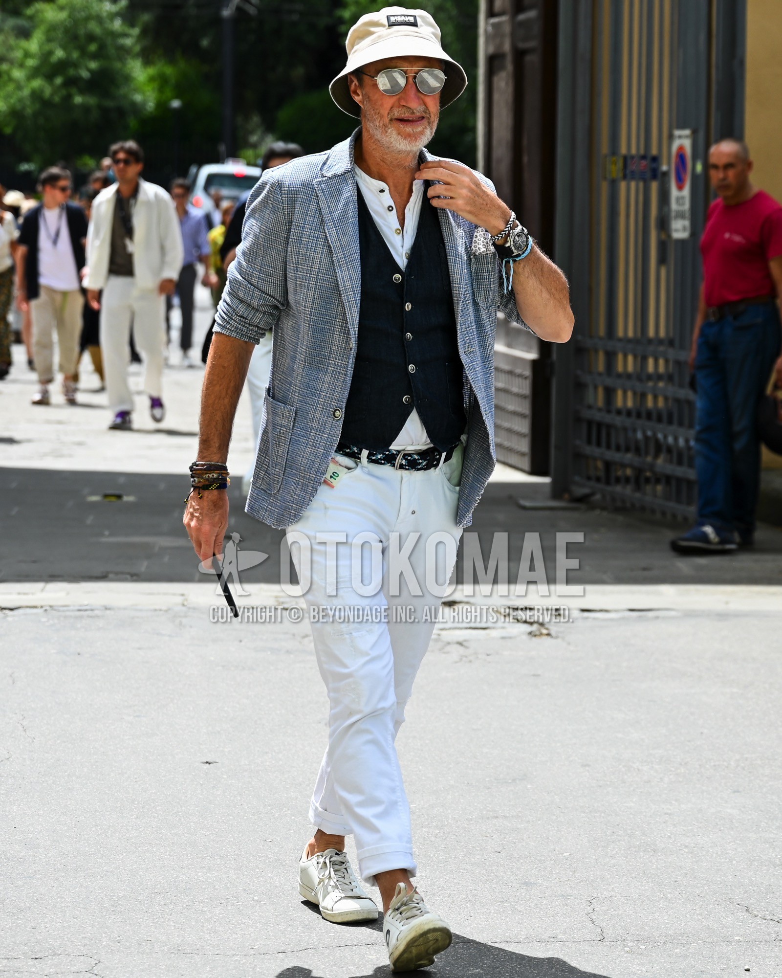 Men's spring summer autumn outfit with beige one point bucket hat, silver plain sunglasses, gray check tailored jacket, white plain shirt, black plain casual vest, black plain leather belt, white plain denim/jeans, white low-cut sneakers.