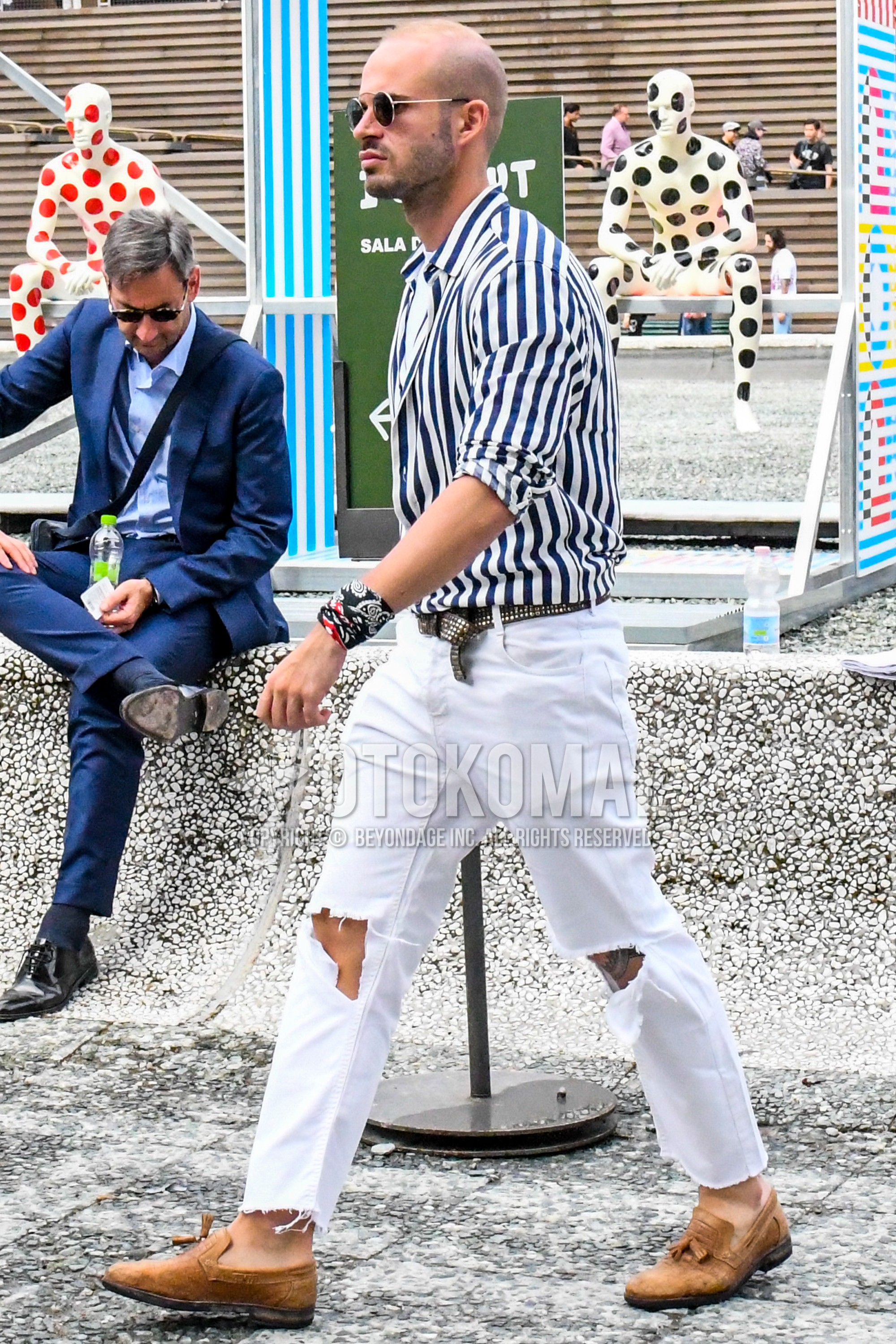 Men's spring summer outfit with plain sunglasses, blue white stripes shirt, brown plain leather belt, white plain damaged jeans, beige tassel loafers leather shoes.