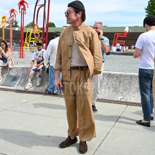 黒無地のキャップ、ゴールド無地のサングラス、スタンドカラーのベージュ無地のシャツジャケット、メッシュの白無地のTシャツ、ブラウン無地のメッシュベルト、ブラウン無地のレザーベルト、ベージュ無地のスラックス、ベージュ無地のプリーツパンツ、ブラウンモカシン/デッキシューズの革靴、ブラウンスエードシューズの革靴、ベージュ無地のカジュアルセットアップを合わせた夏春のメンズコーデ・着こなし。