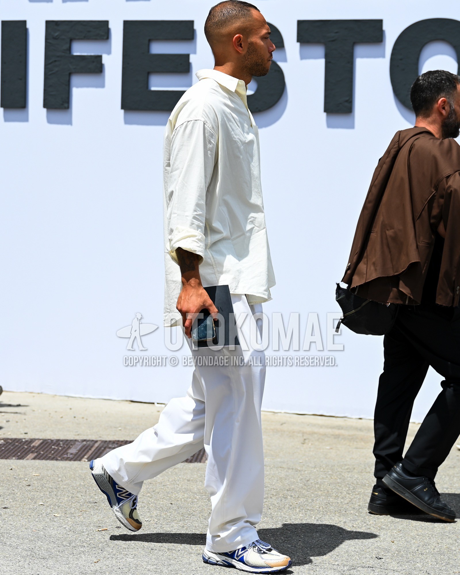 Men's spring summer outfit with white plain shirt, white plain wide pants, white blue low-cut sneakers.