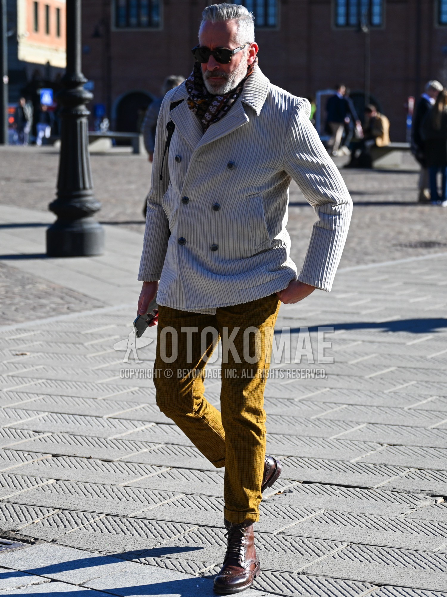 Men's autumn winter outfit with olive green plain sunglasses, beige brown graphic scarf, white plain ulster coat, yellow check ankle pants, brown work boots.