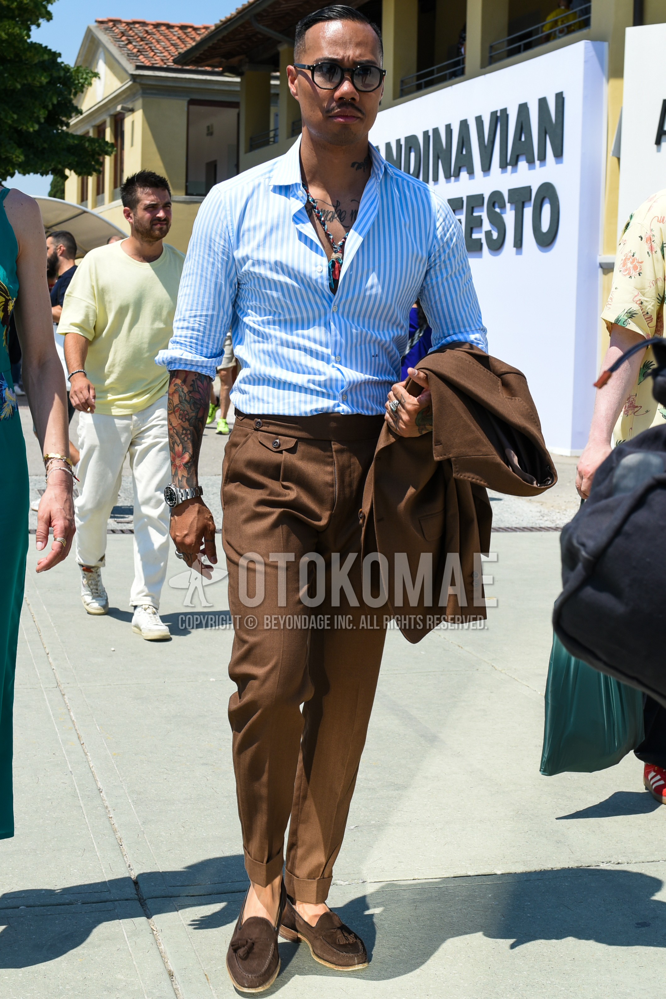 Men's spring summer outfit with black plain sunglasses, light blue stripes shirt, brown tassel loafers leather shoes, brown suede shoes leather shoes, brown plain suit.