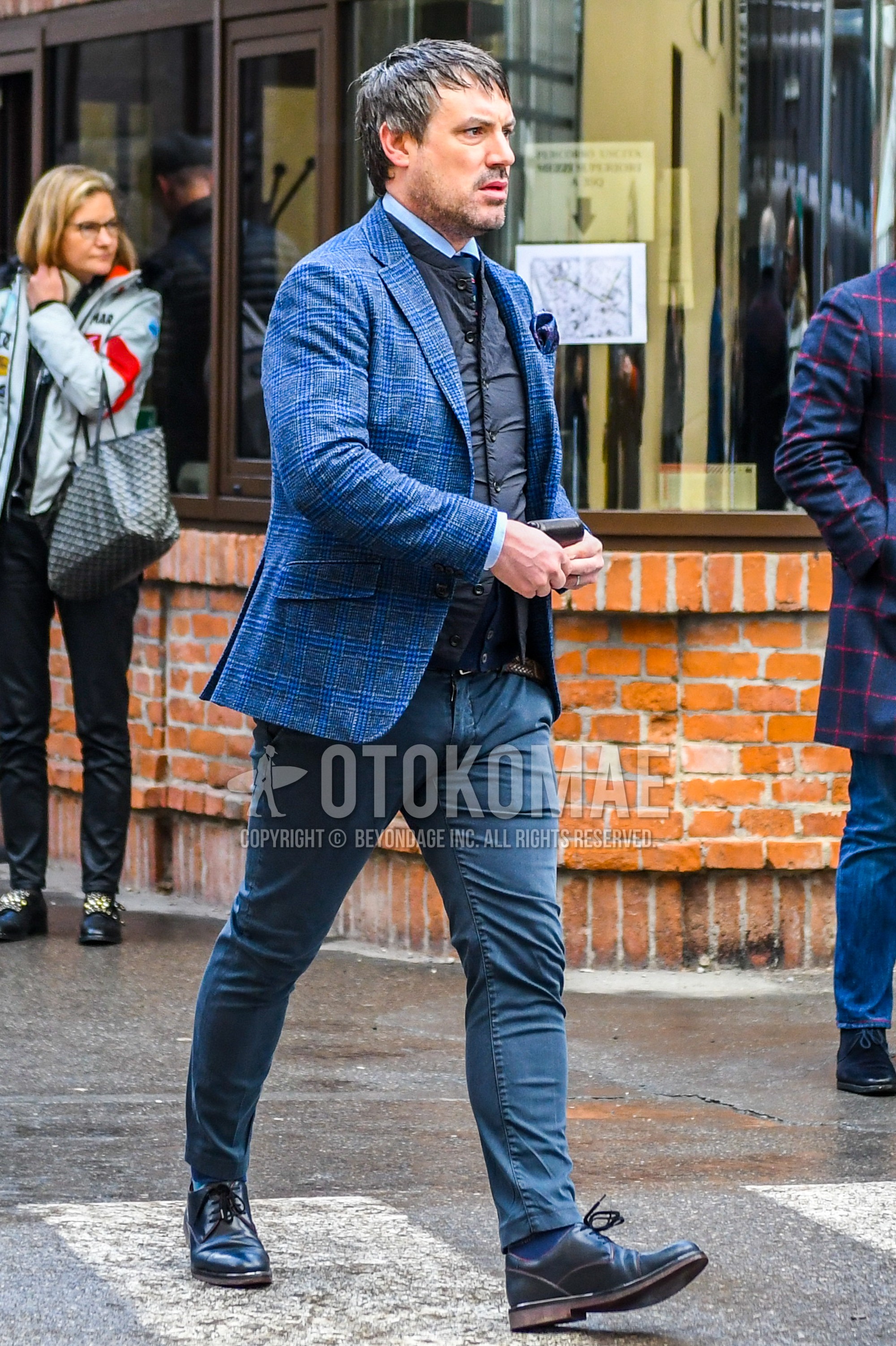 Men's winter outfit with blue check tailored jacket, black plain inner down, dark gray plain chinos, blue plain socks, blue plain toe leather shoes.
