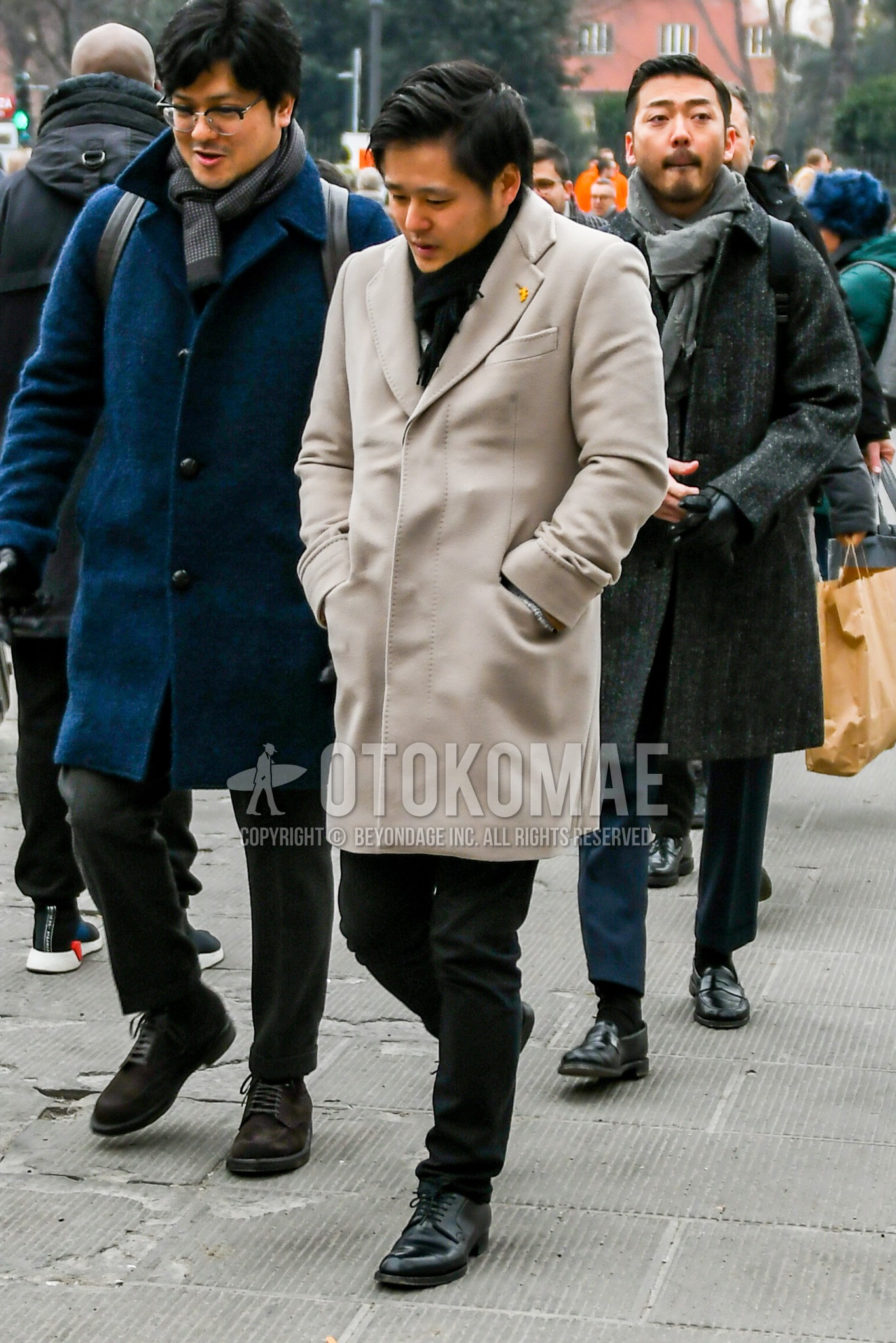 Men's winter outfit with black plain scarf, beige plain chester coat, black plain cotton pants, black plain toe leather shoes.