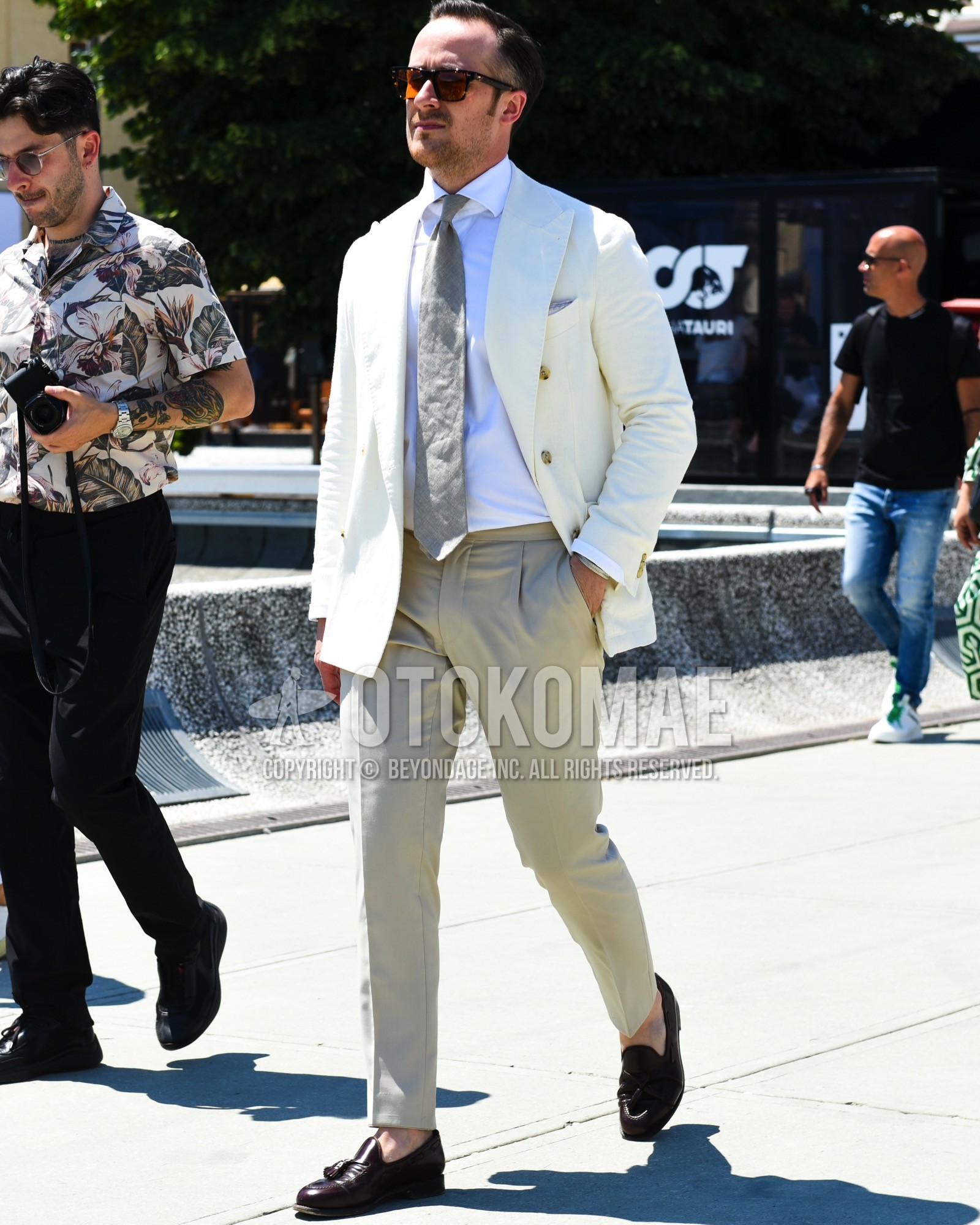 Men's spring summer outfit with black tortoiseshell sunglasses, white plain tailored jacket, white plain shirt, beige plain slacks, brown tassel loafers leather shoes, gray plain necktie.