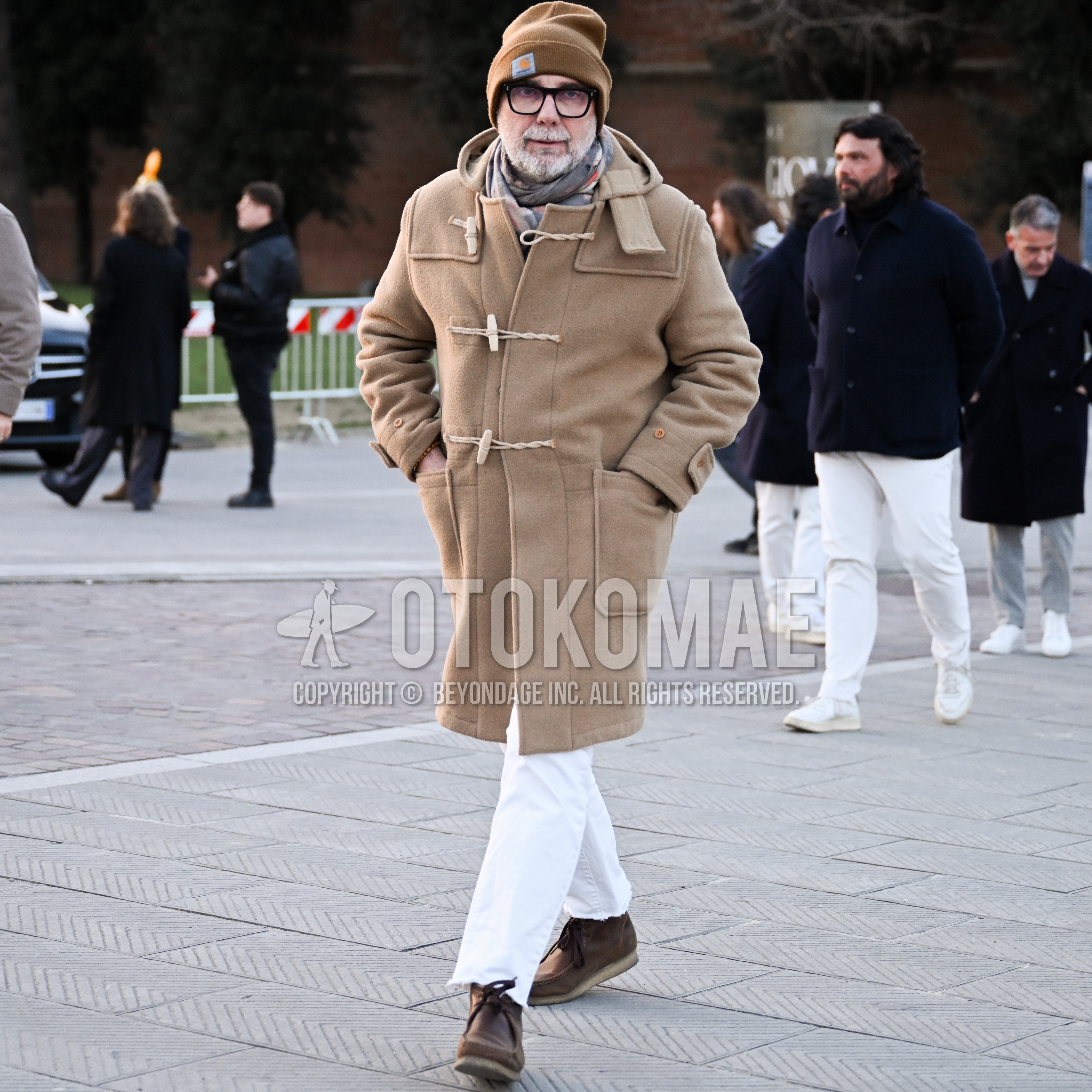 Men's autumn winter outfit with beige one point knit cap, black plain glasses, whole pattern scarf, beige plain duffle coat, white plain denim/jeans, brown  boots.