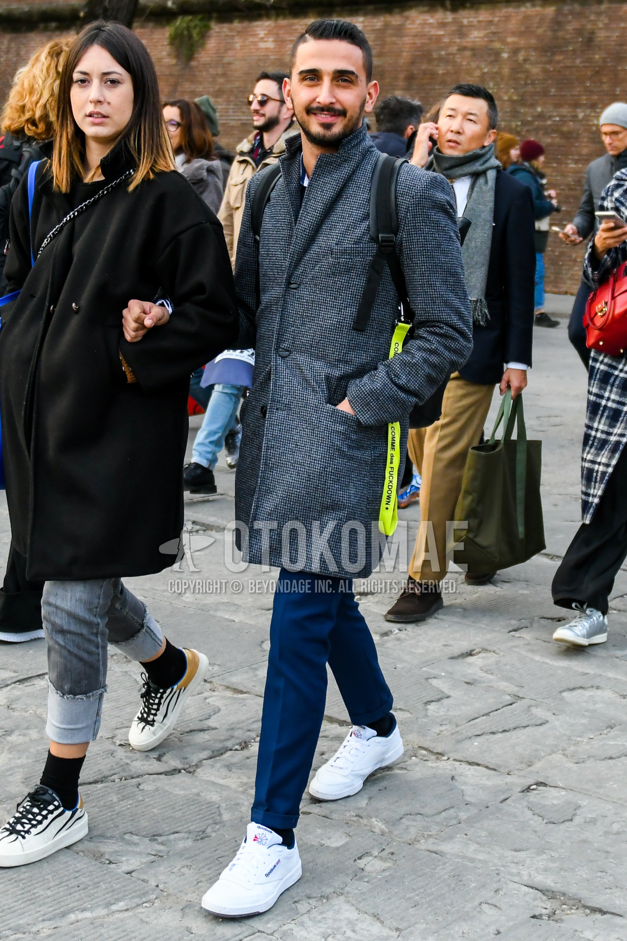 Men's winter outfit with gray plain chester coat, blue plain slacks, black plain socks, white low-cut sneakers.