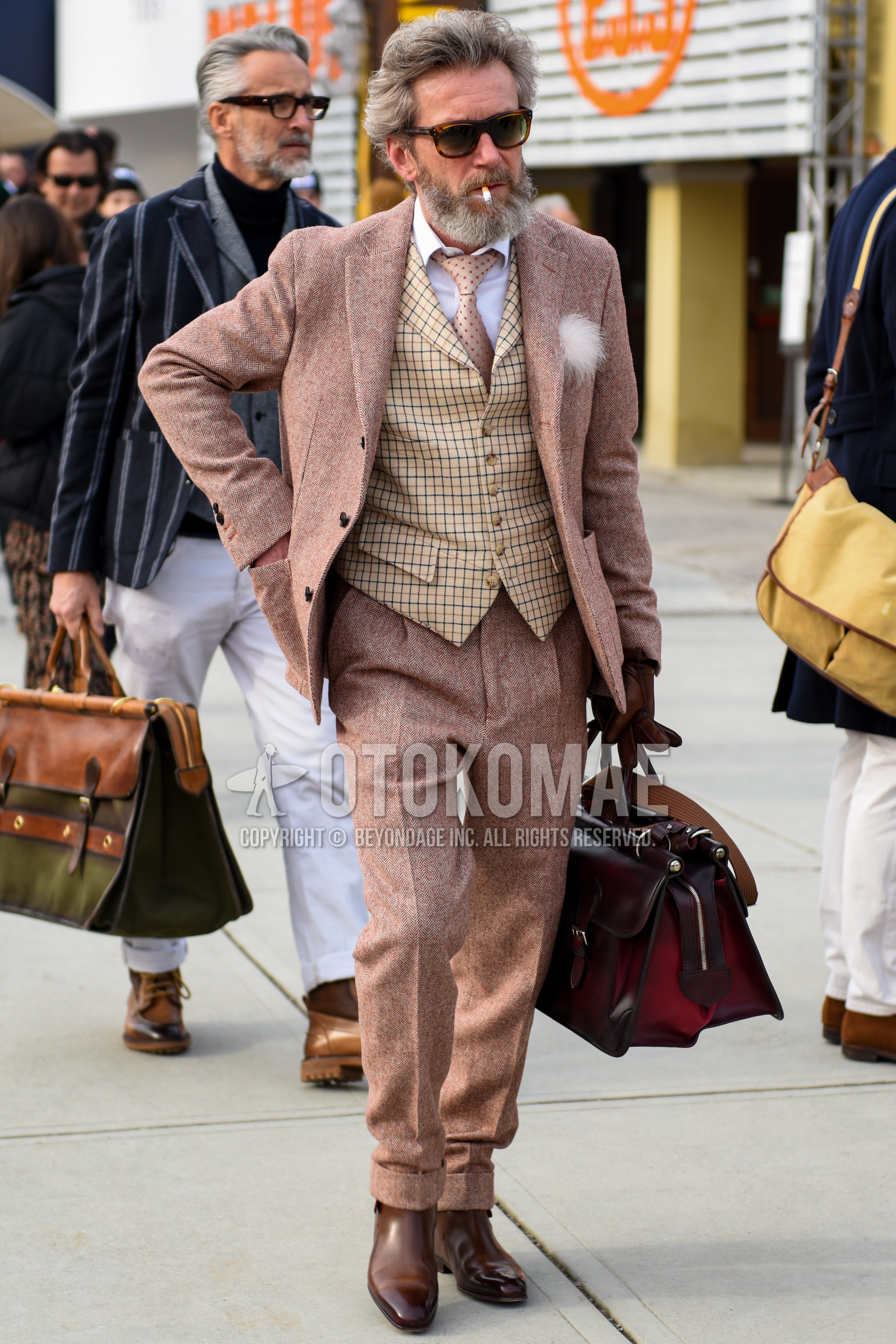 Men's autumn winter outfit with brown tortoiseshell sunglasses, beige check gilet, brown country boots, pink herringbone suit, pink dots necktie.
