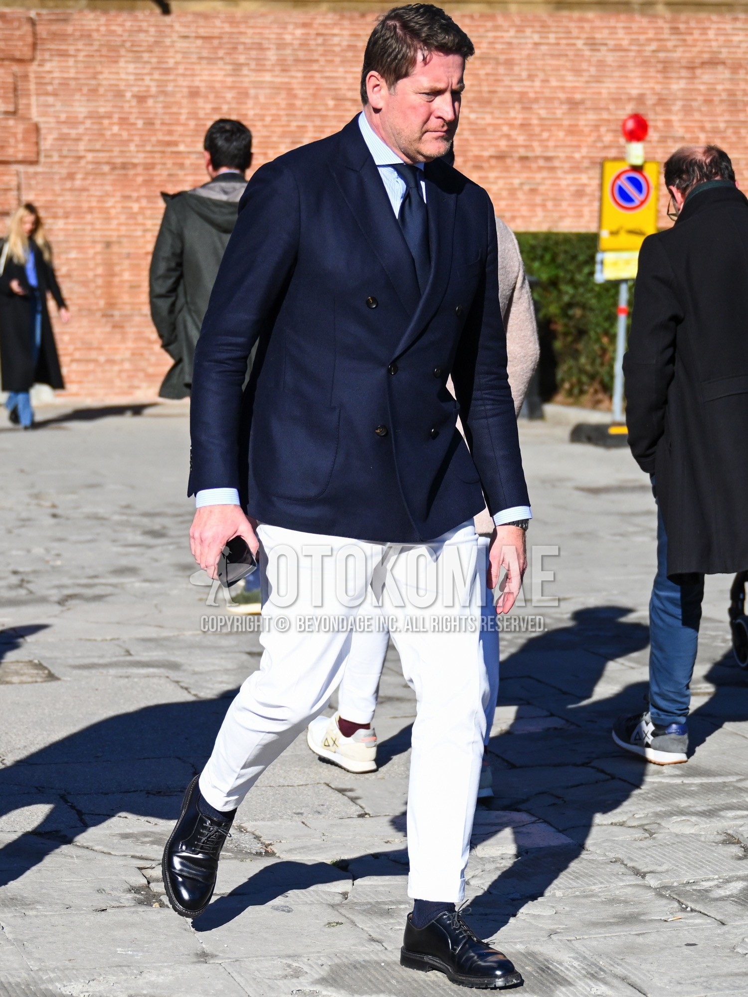 Men's spring autumn winter outfit with navy plain tailored jacket, blue stripes shirt, white plain cotton pants, navy plain socks, black plain toe leather shoes, navy plain necktie.