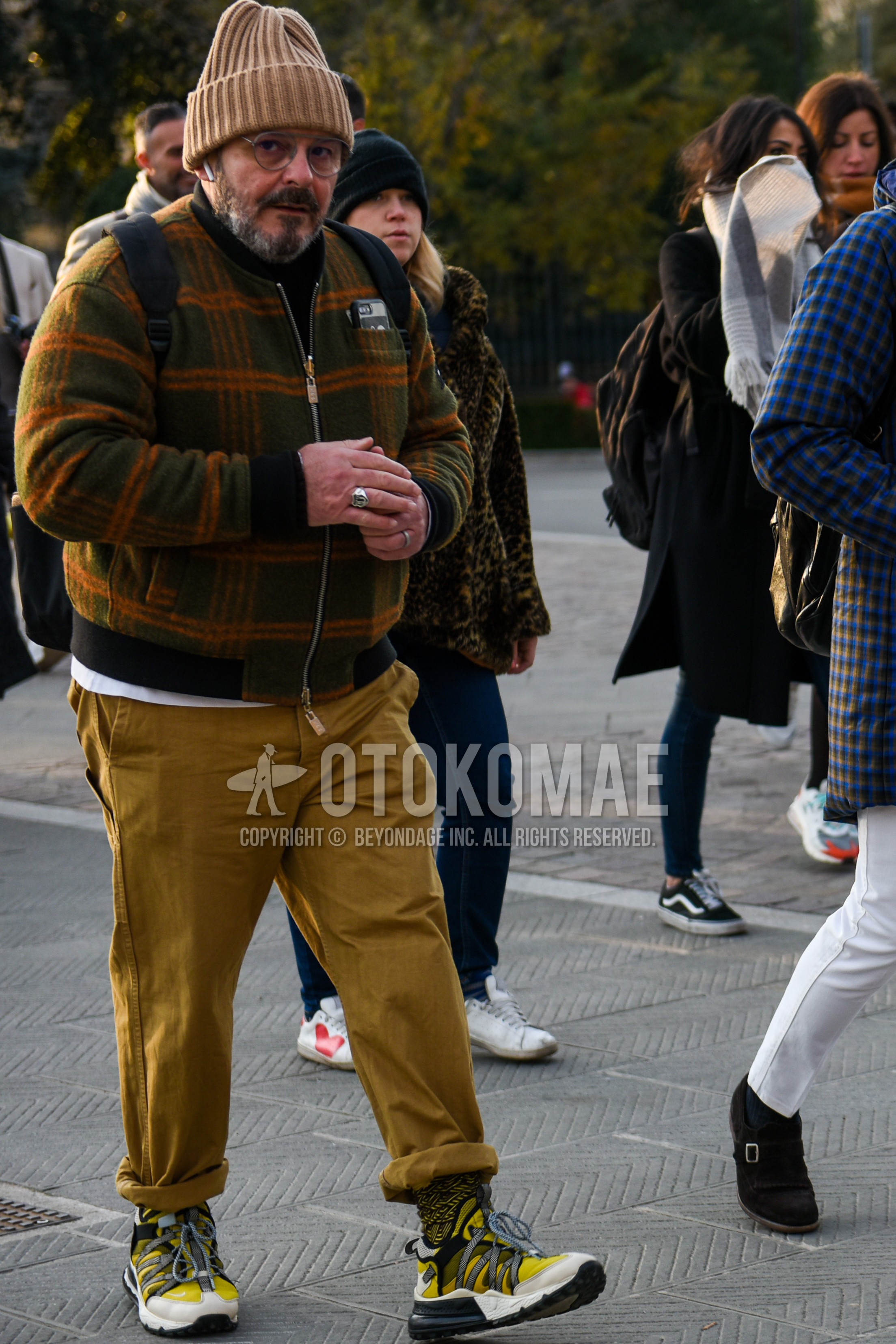 Men's autumn winter outfit with beige plain knit cap, gray plain glasses, multi-color check MA-1, beige plain chinos, yellow socks socks, yellow low-cut sneakers.