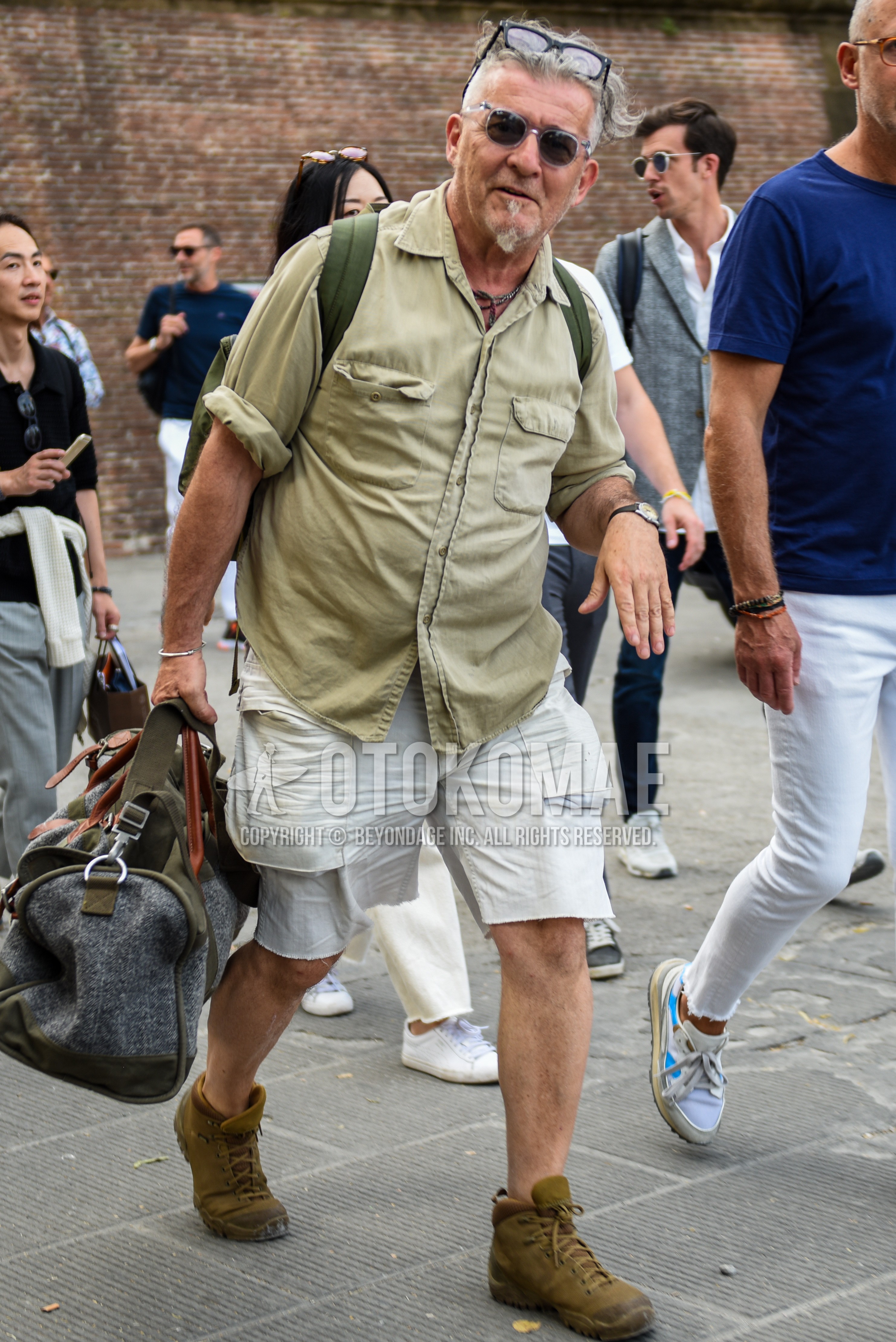 Men's summer outfit with clear plain sunglasses, beige plain shirt, white plain short pants, brown high-cut sneakers, gray plain boston bag.
