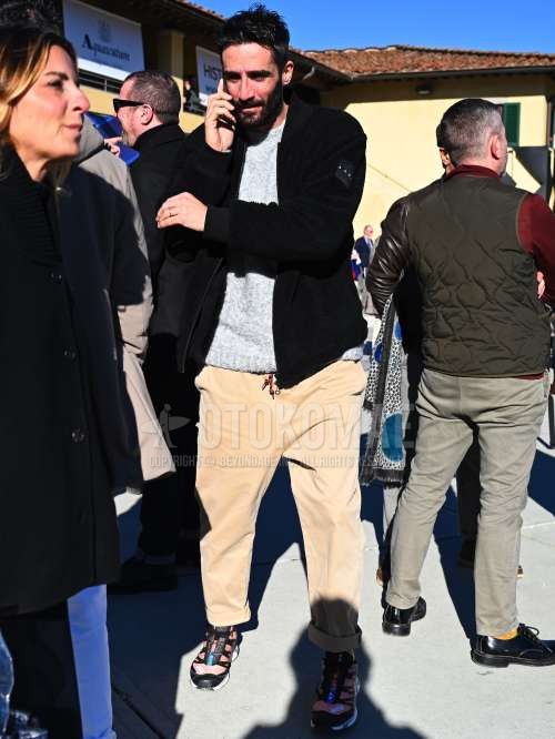 黒無地のスタジャン、黒無地のフリースジャケット、グレー無地のセーター、ベージュ無地のチノパン、ピンク・黒ローカットのスニーカーを合わせた秋冬春のメンズコーデ・着こなし。