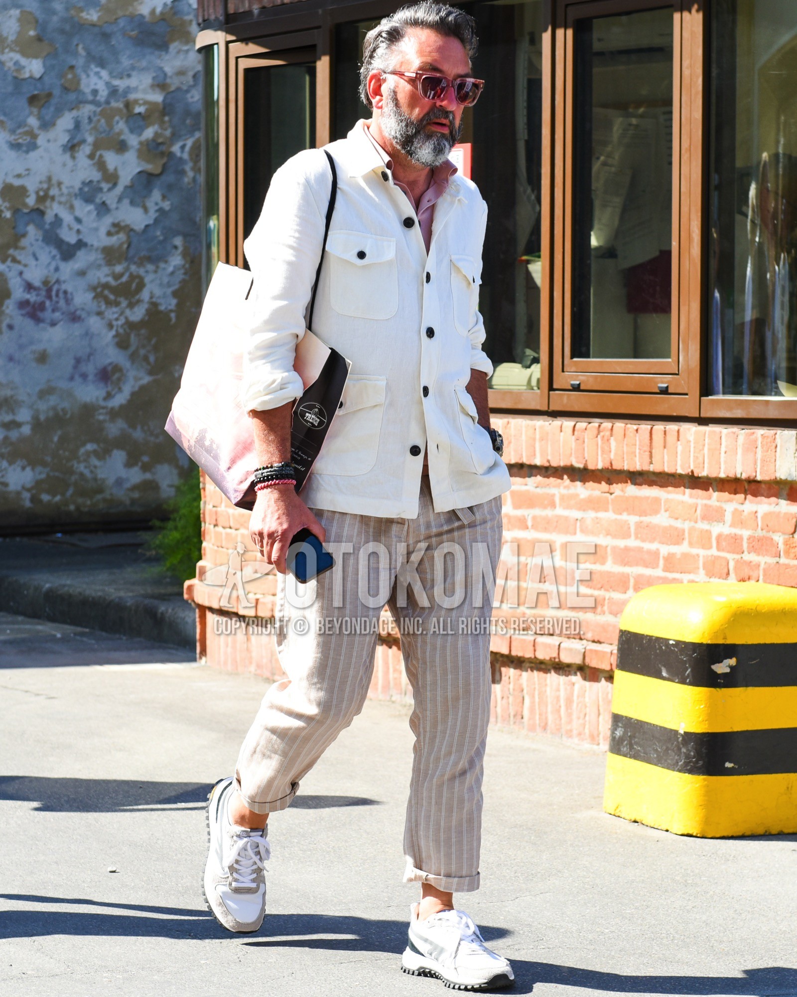 Men's spring summer outfit with brown plain sunglasses, white plain coverall, pink plain shirt, beige stripes slacks, white low-cut sneakers.