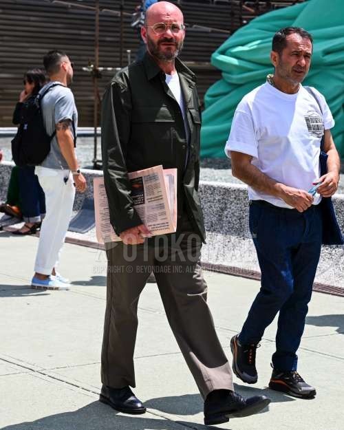 クリア無地のサングラス、黒・オリーブグリーン無地のミリタリージャケット(MA-1、M-65以外)、白無地のTシャツ、ベージュ無地のスラックス、黒のブーツを合わせた春秋夏のメンズコーデ・着こなし。