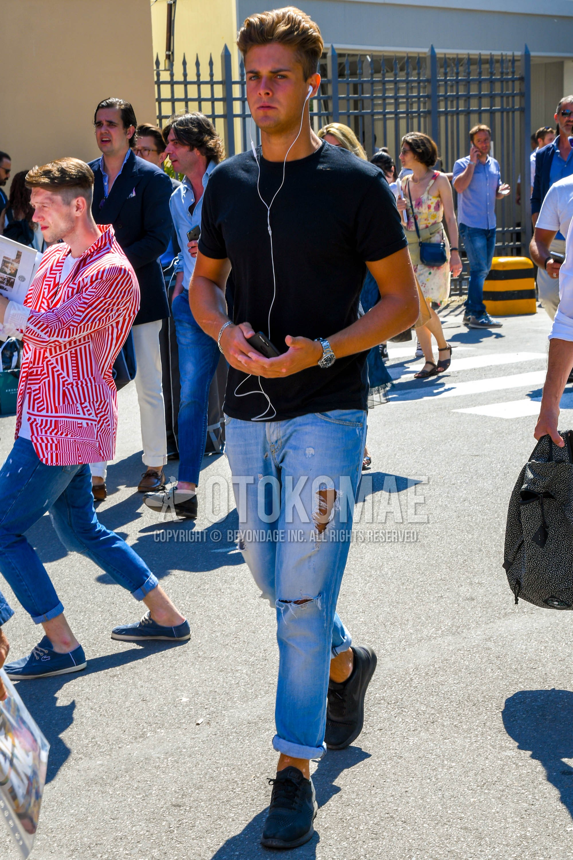 Men's summer outfit with black plain t-shirt, blue plain damaged jeans, black low-cut sneakers.