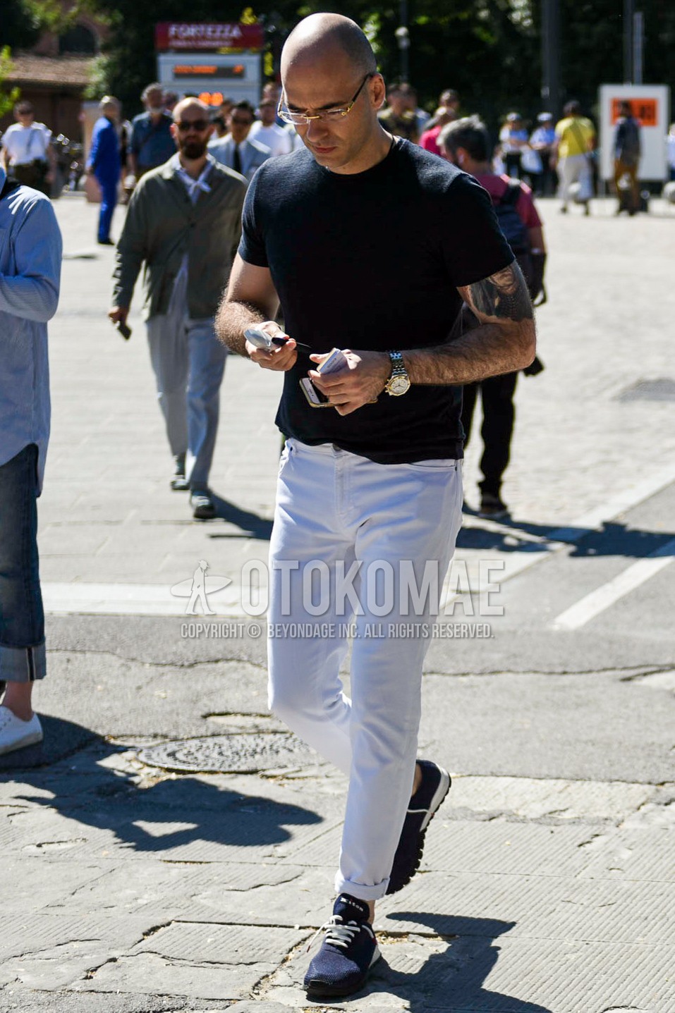 Men's summer outfit with plain glasses, black plain t-shirt, white plain cotton pants, navy low-cut sneakers.