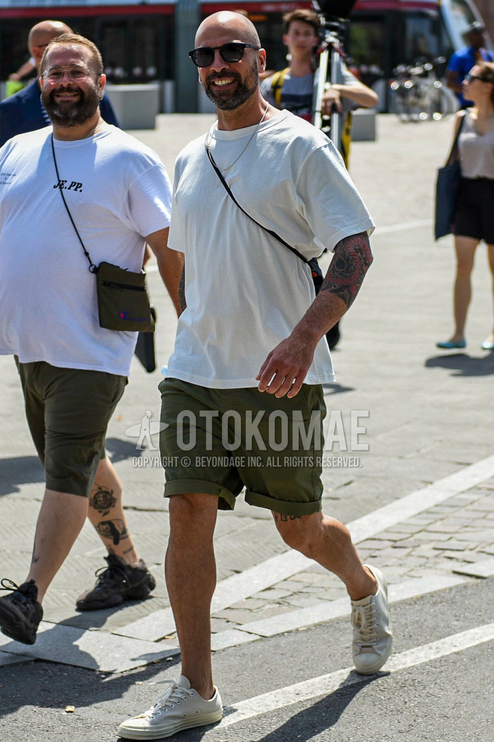 Men's summer outfit with black plain sunglasses, white plain t-shirt, olive green plain short pants, white low-cut sneakers.