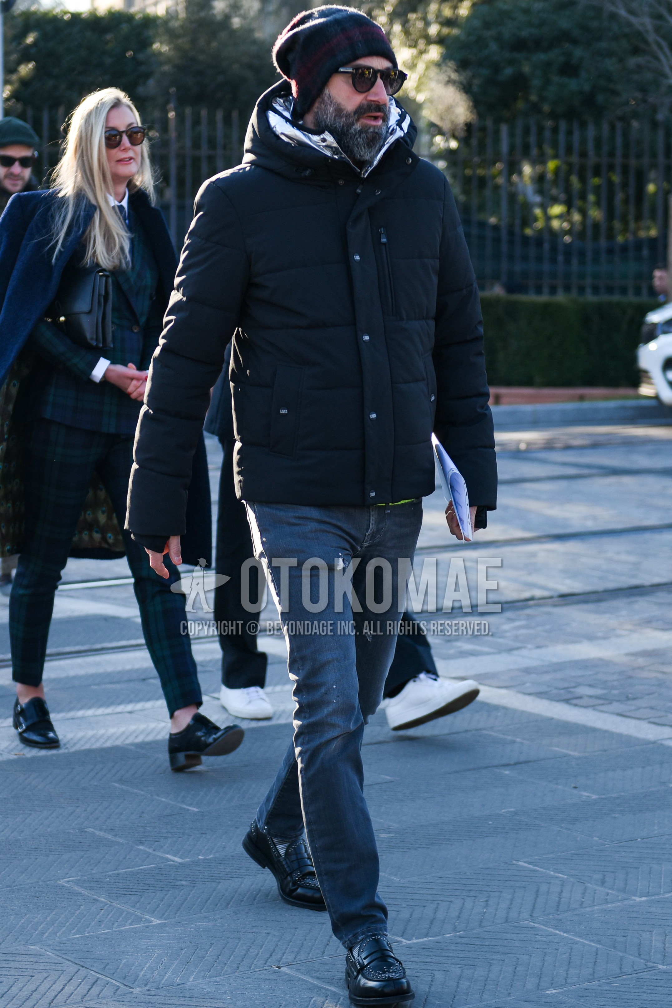 Men's autumn winter outfit with multi-color check knit cap, black plain sunglasses, black plain down jacket, gray plain denim/jeans, black coin loafers leather shoes.
