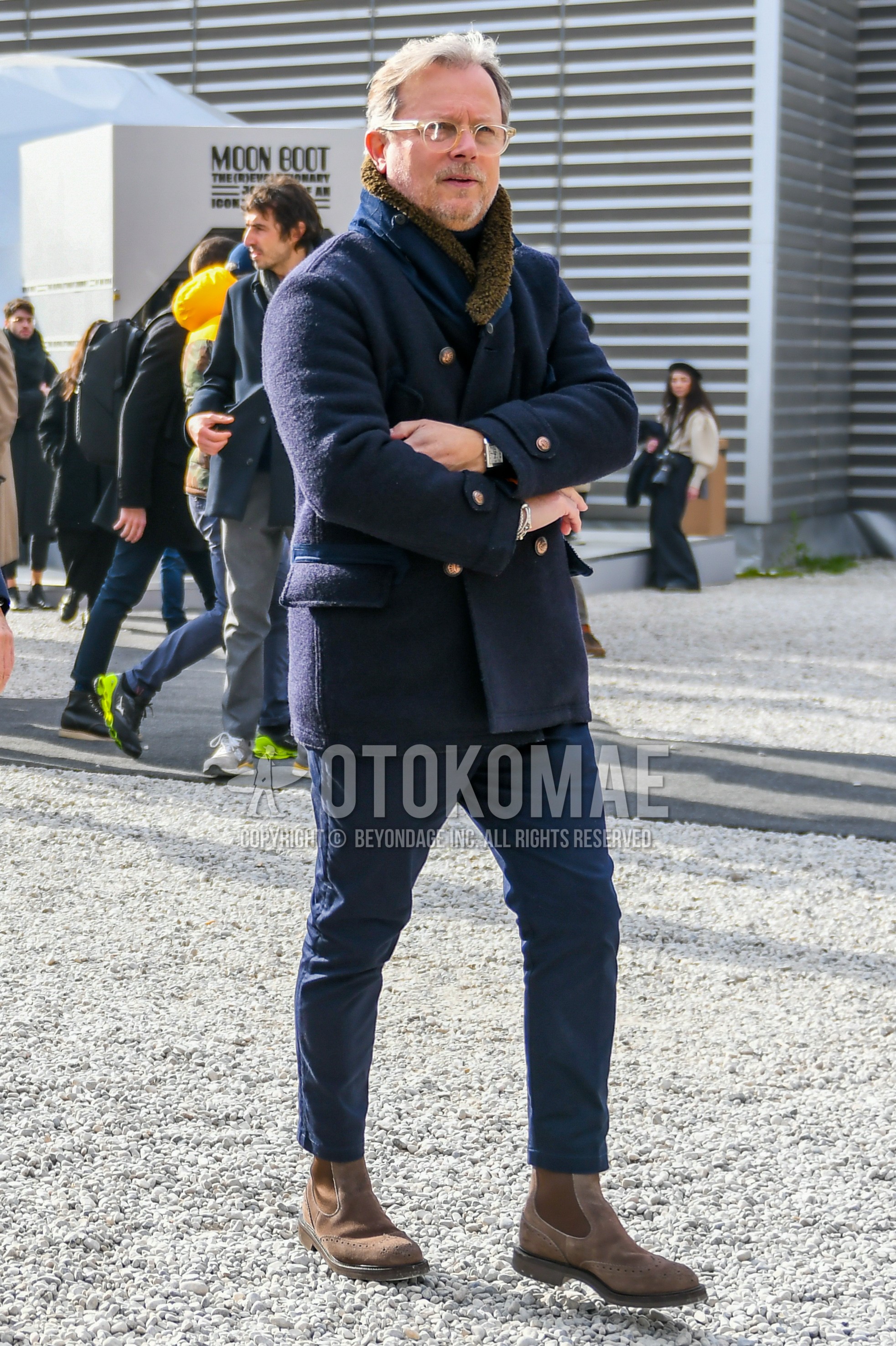 Men's winter outfit with plain glasses, navy plain outerwear, navy plain chinos, brown side-gore boots.
