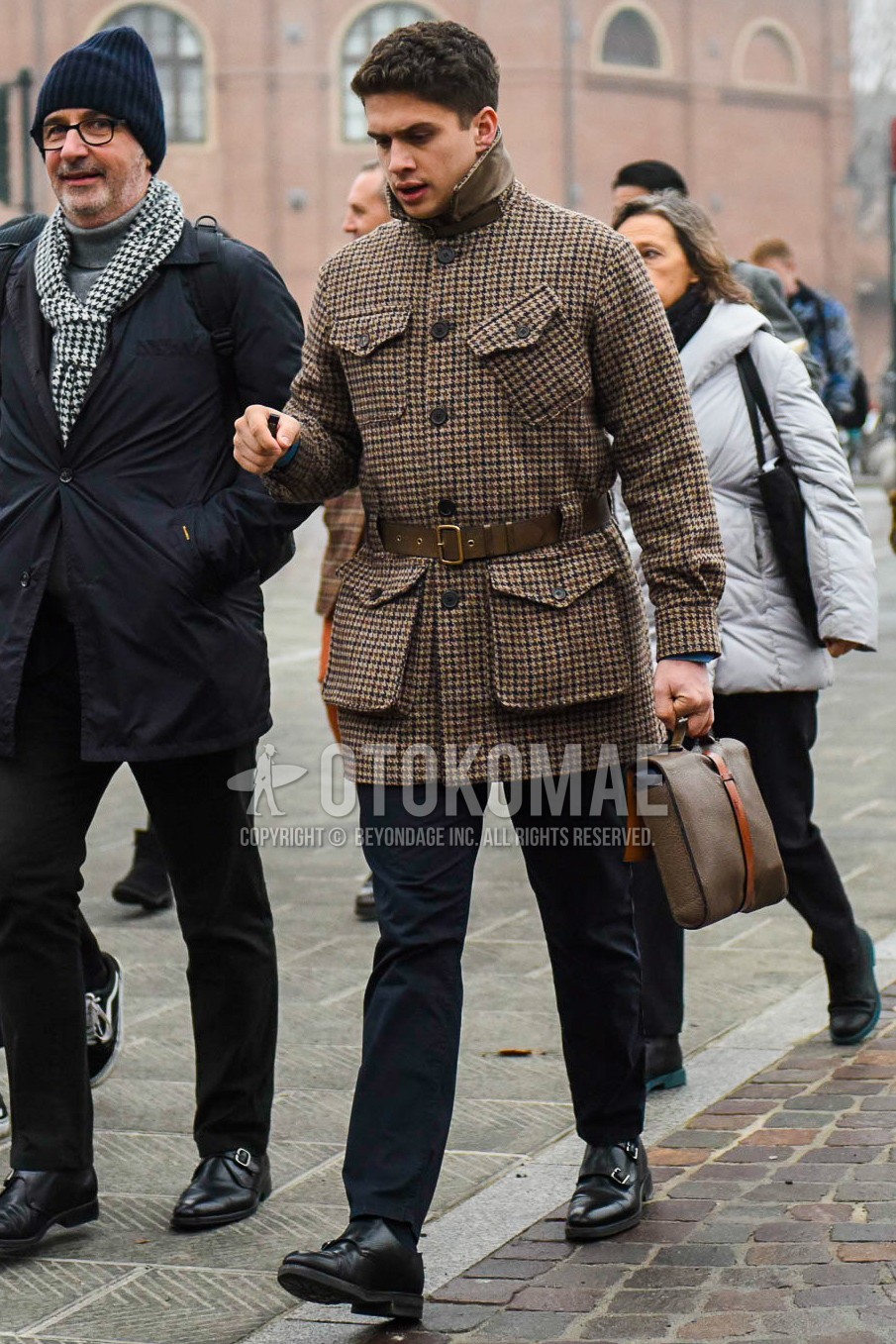 Men's winter outfit with brown check belted coat, navy plain slacks, black monk shoes leather shoes.