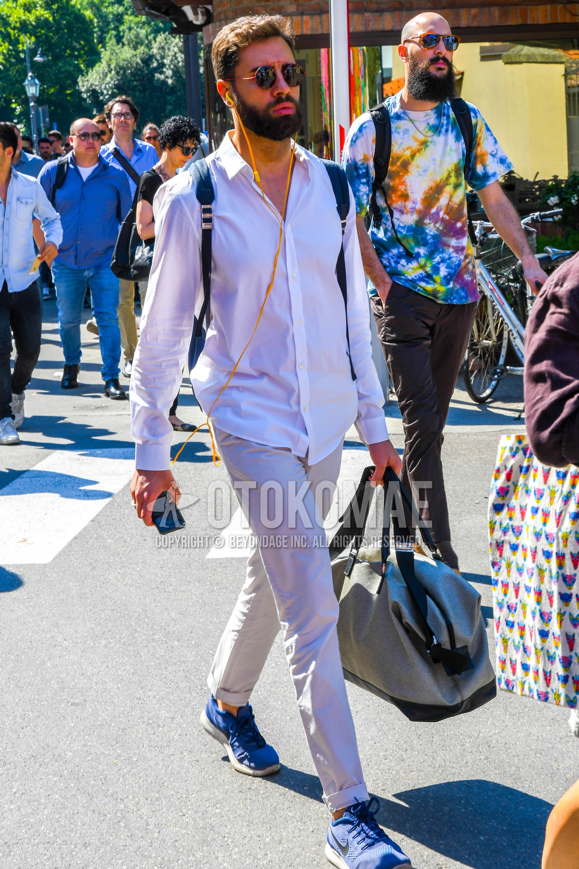Men's spring summer autumn outfit with plain sunglasses, white plain shirt, white plain chinos, blue sneakers, gray plain briefcase/handbag.