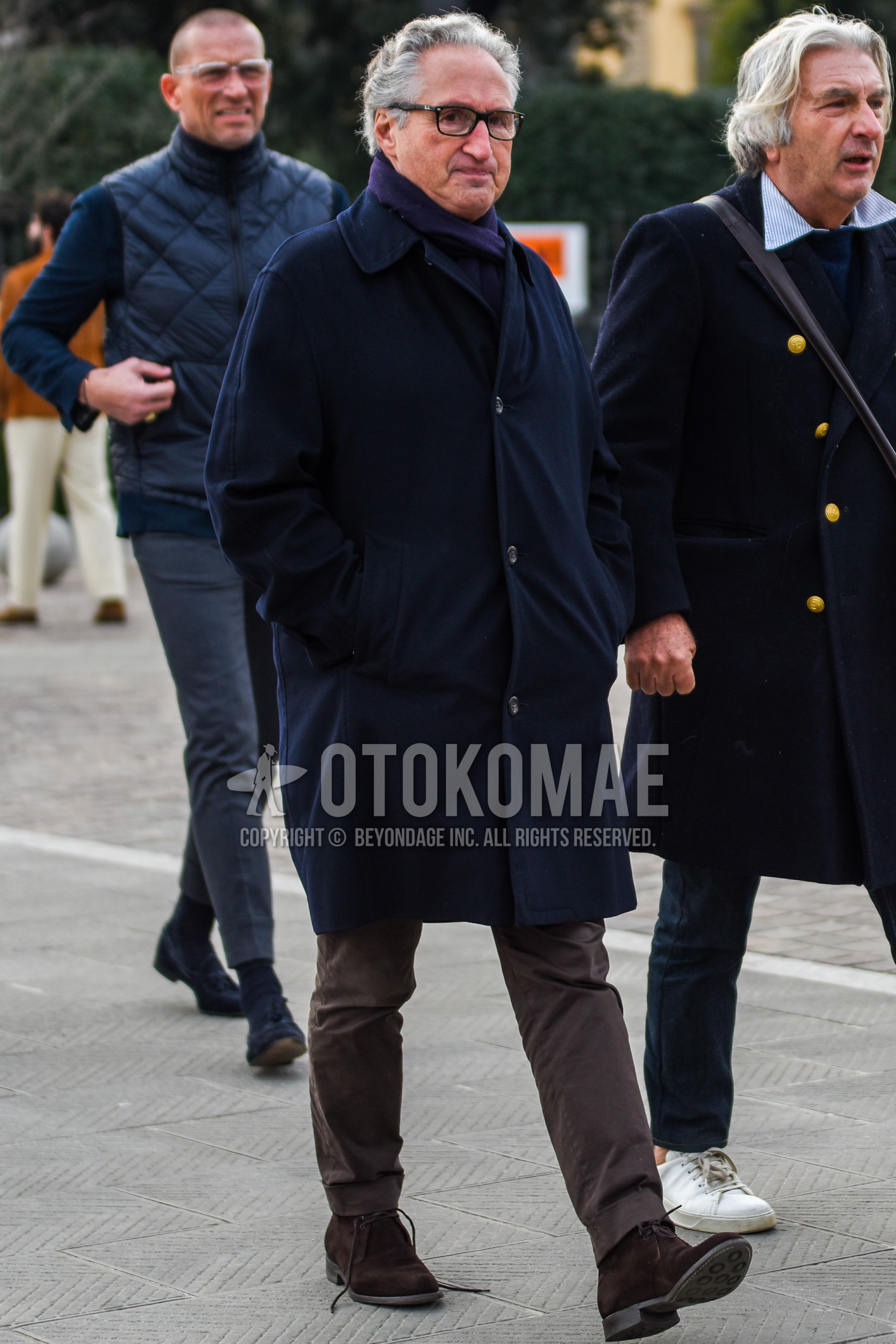 Men's autumn winter outfit with black plain glasses, purple plain scarf, navy plain stenkarrer coat, brown plain cotton pants, brown chukka boots.