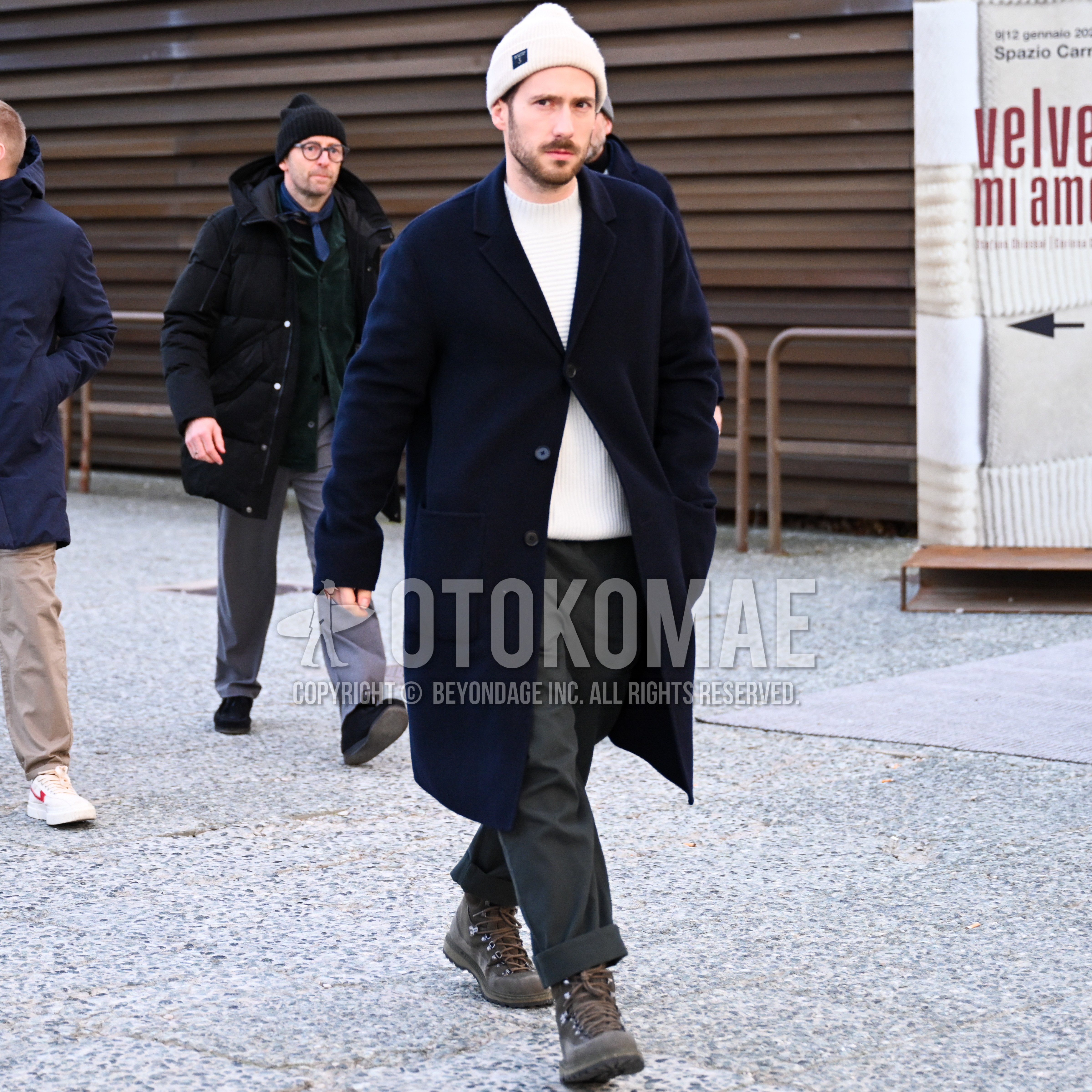 Men's spring autumn winter outfit with white one point knit cap, navy plain chester coat, white plain sweater, dark gray plain wide pants, brown work boots.