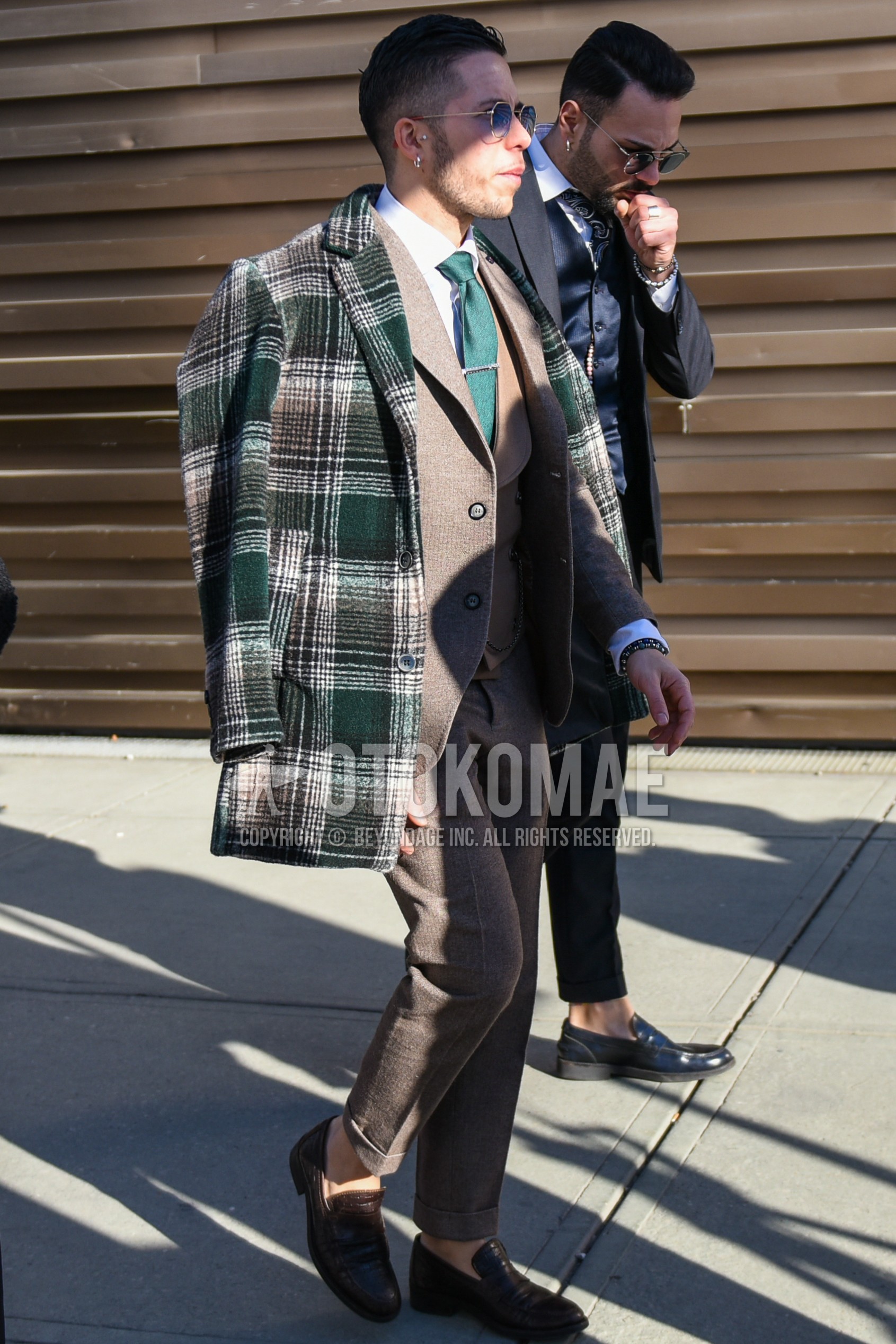 Men's autumn winter outfit with gold plain sunglasses, green check tailored jacket, white plain shirt, brown coin loafers leather shoes, beige plain suit, green plain necktie.