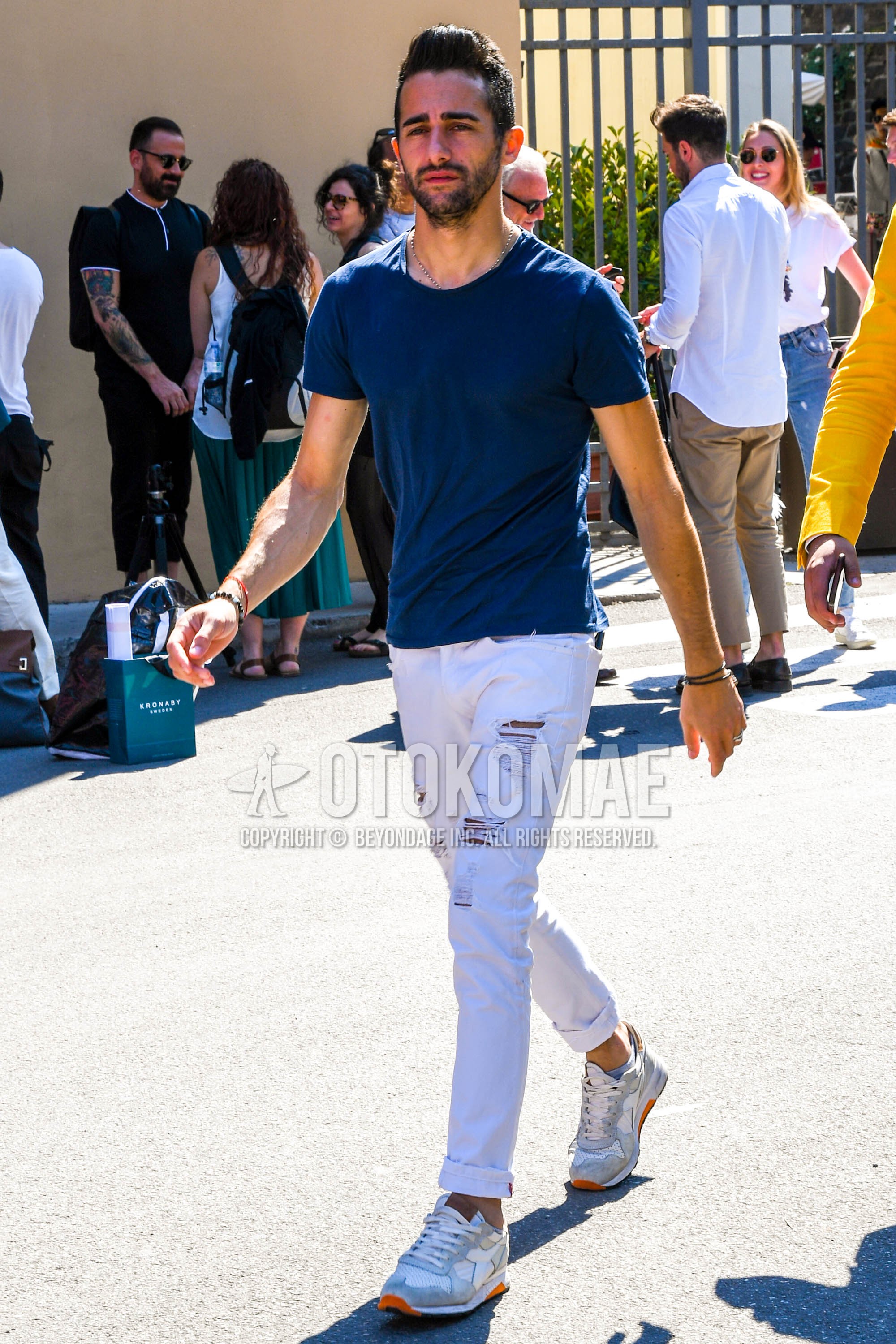 Men's summer outfit with navy plain t-shirt, white plain damaged jeans, white low-cut sneakers.