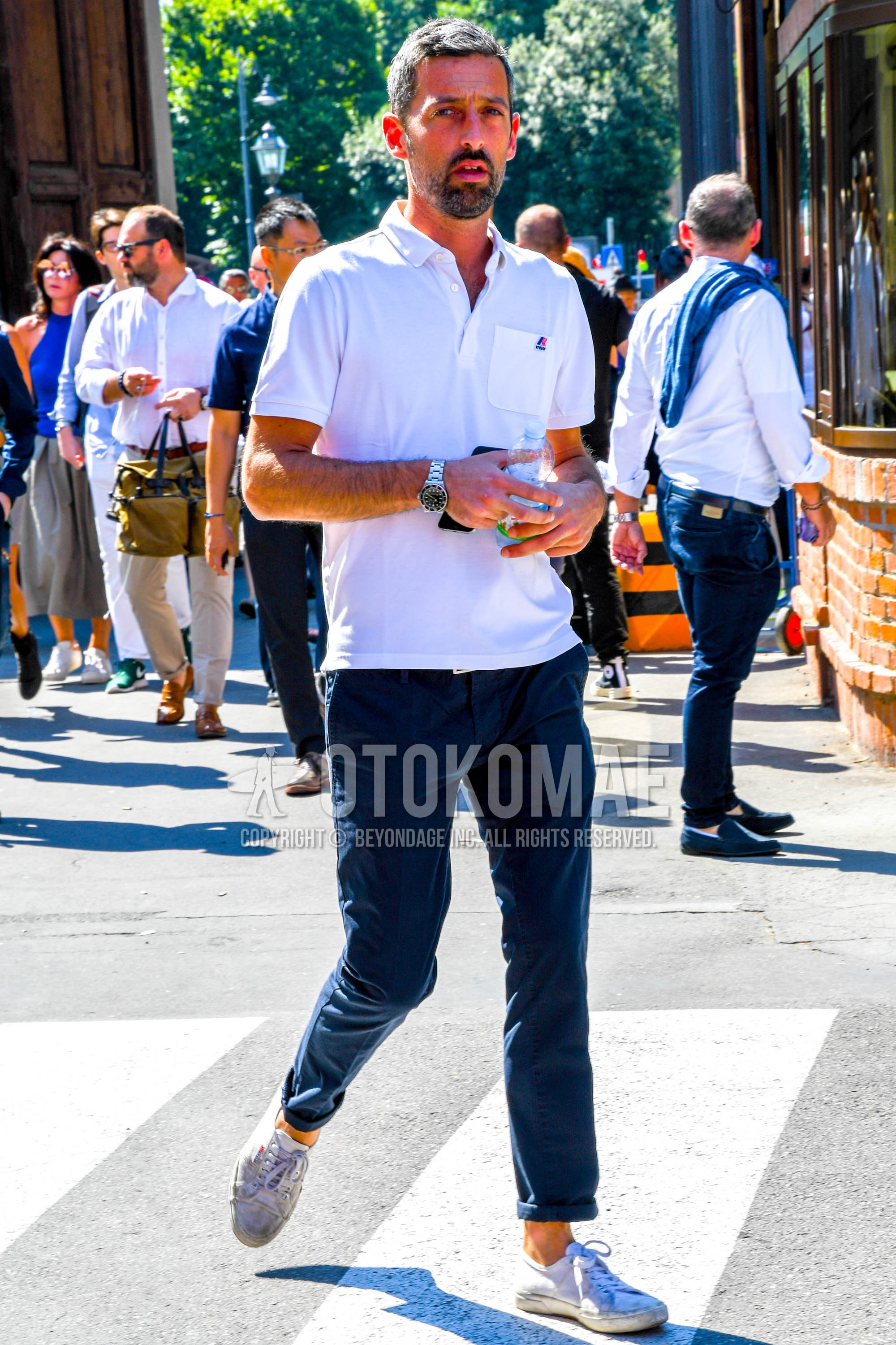 Men's summer outfit with white plain polo shirt, navy plain chinos, white low-cut sneakers.