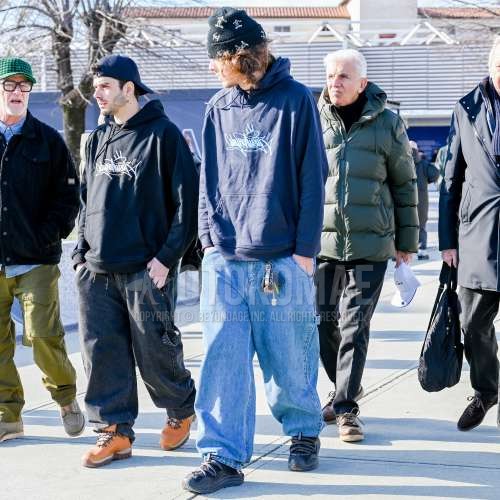 黒キャップのニットキャップ、黒グラフィックのフーディ、ブルー無地のデニム/ジーンズ、黒ローカットのスニーカーを合わせた春秋のメンズコーデ・着こなし。