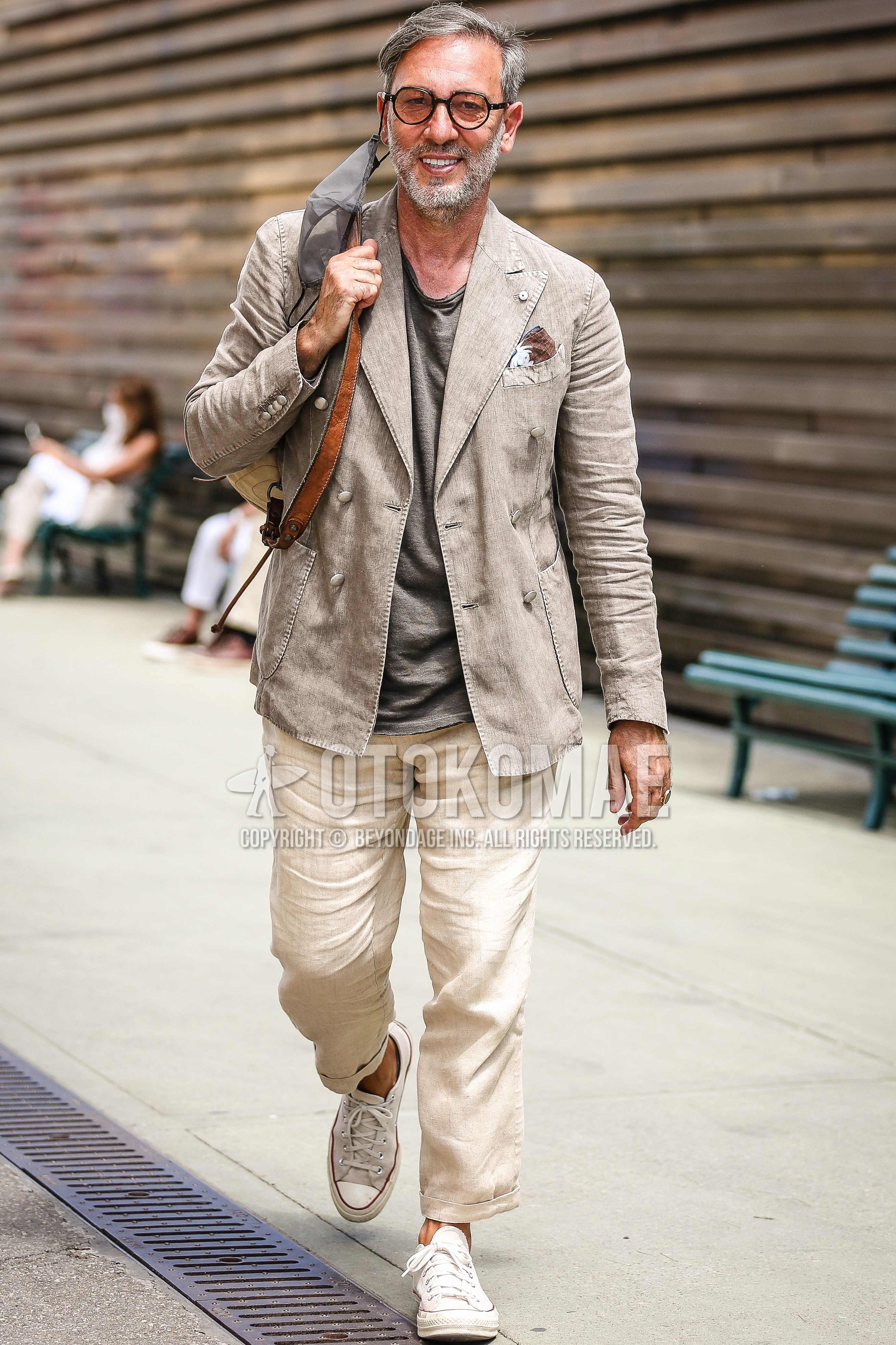 Men's spring summer outfit with gray beige plain tailored jacket, gray plain t-shirt, beige plain easy pants, beige plain cropped pants, white sneakers, brown plain backpack.