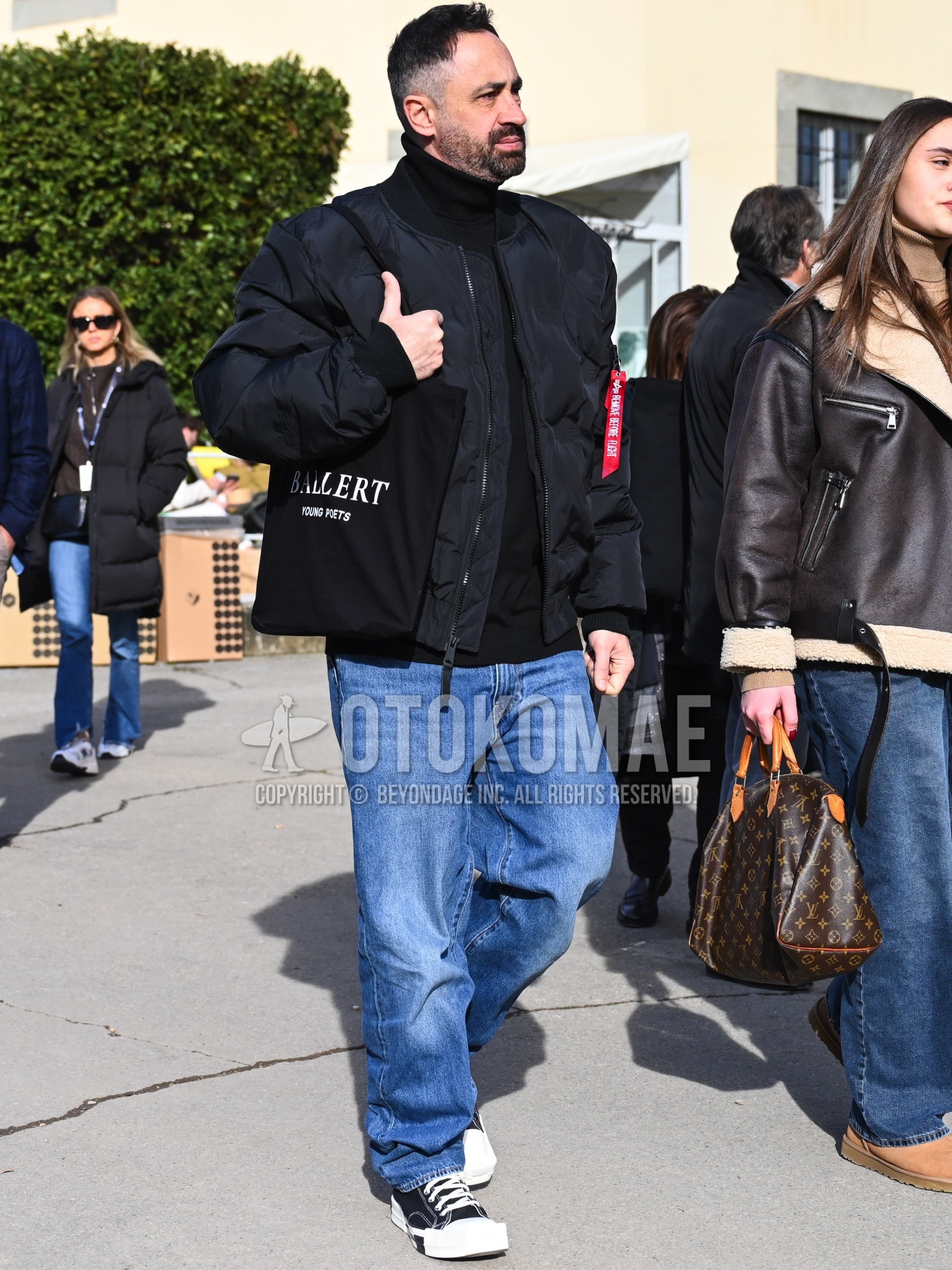 Men's spring autumn winter outfit with black plain MA-1, black plain turtleneck knit, blue plain denim/jeans, black low-cut sneakers, black deca logo tote bag.