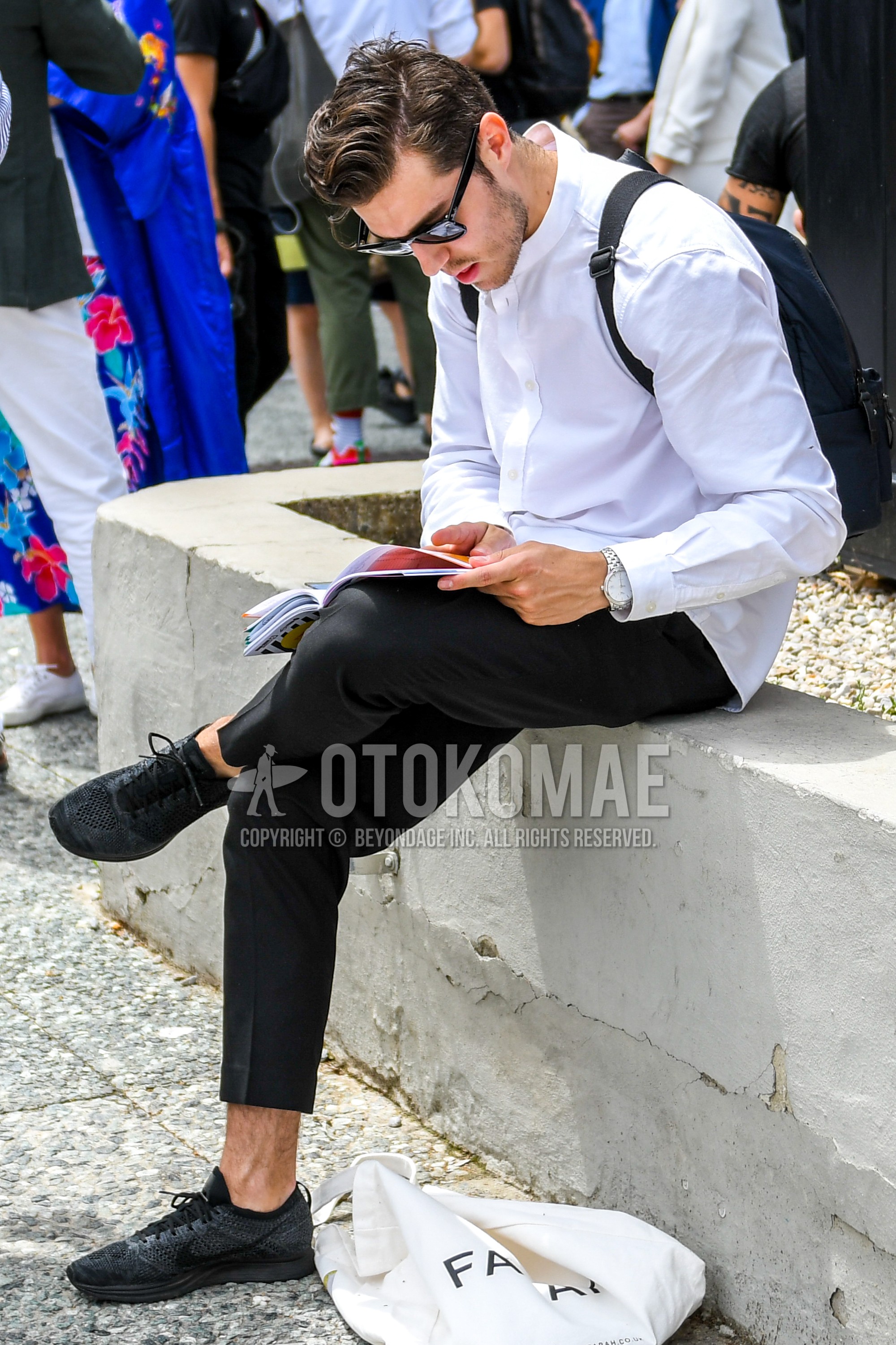 Men's spring summer autumn outfit with plain sunglasses, white plain shirt, black plain slacks, black low-cut sneakers, black plain backpack.