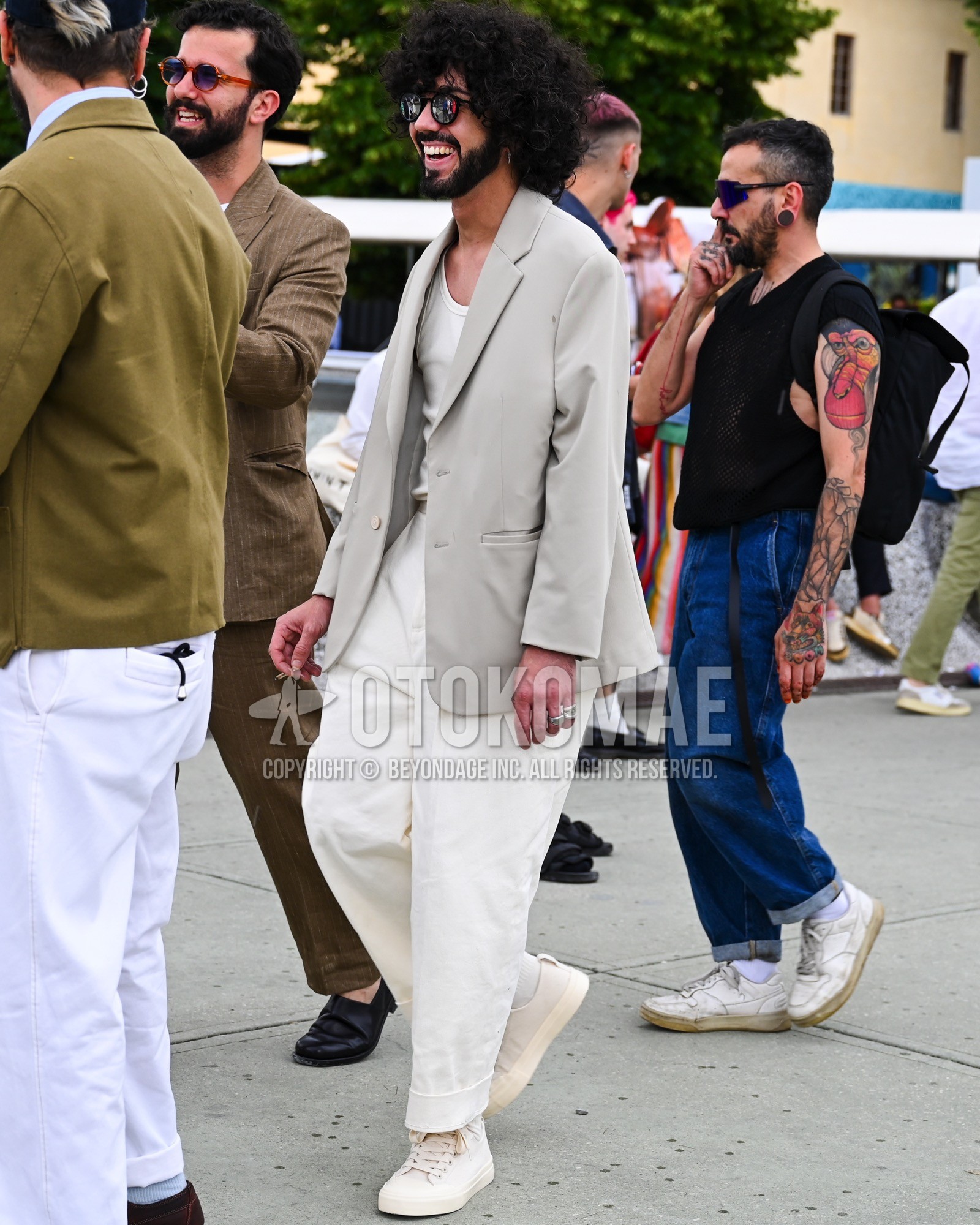 Men's spring summer autumn outfit with silver plain sunglasses, beige plain tailored jacket, white plain t-shirt, white plain wide pants, white low-cut sneakers.